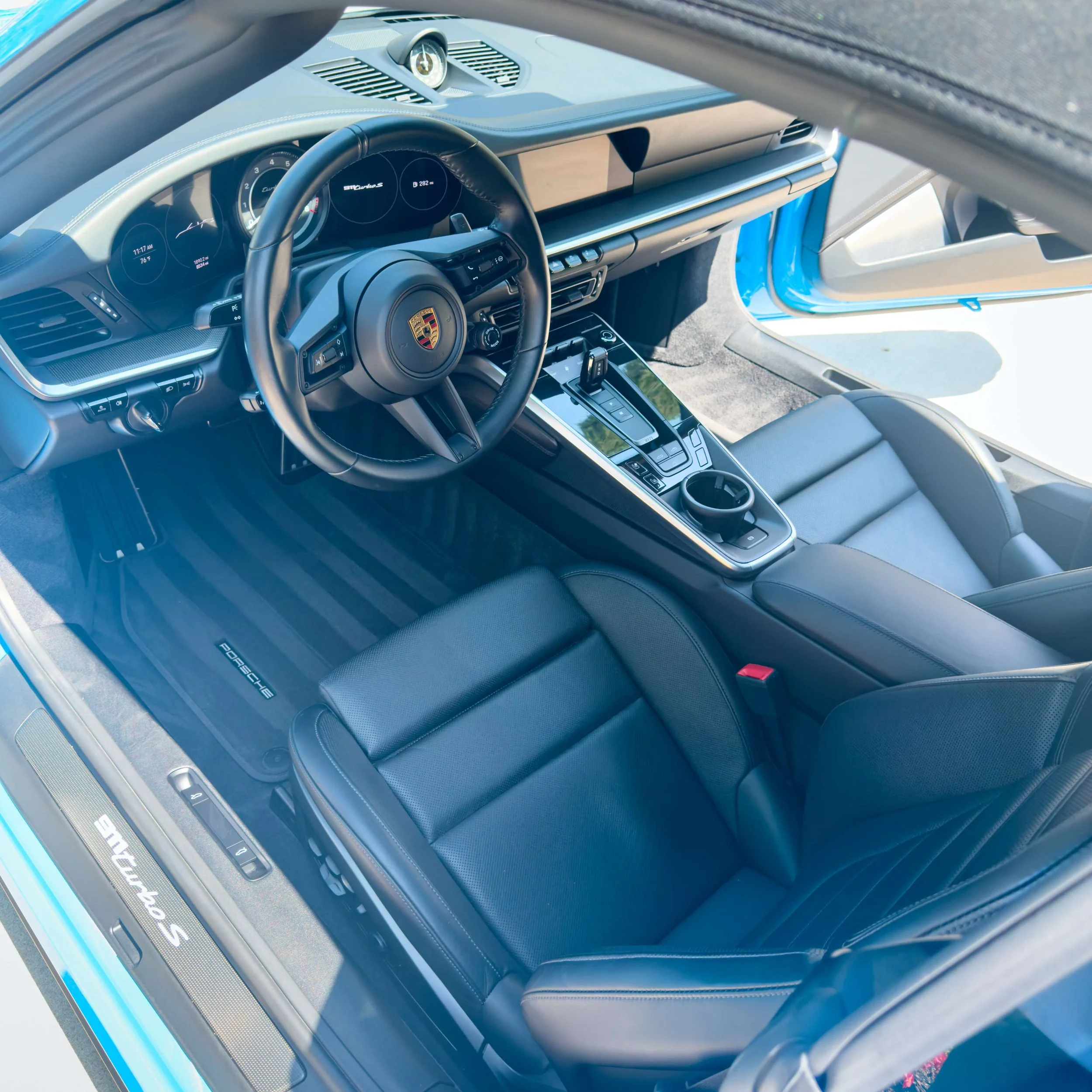 Interior of a modern Porsche sports car with black leather seats, a sleek dashboard, and a central console with electronic controls.