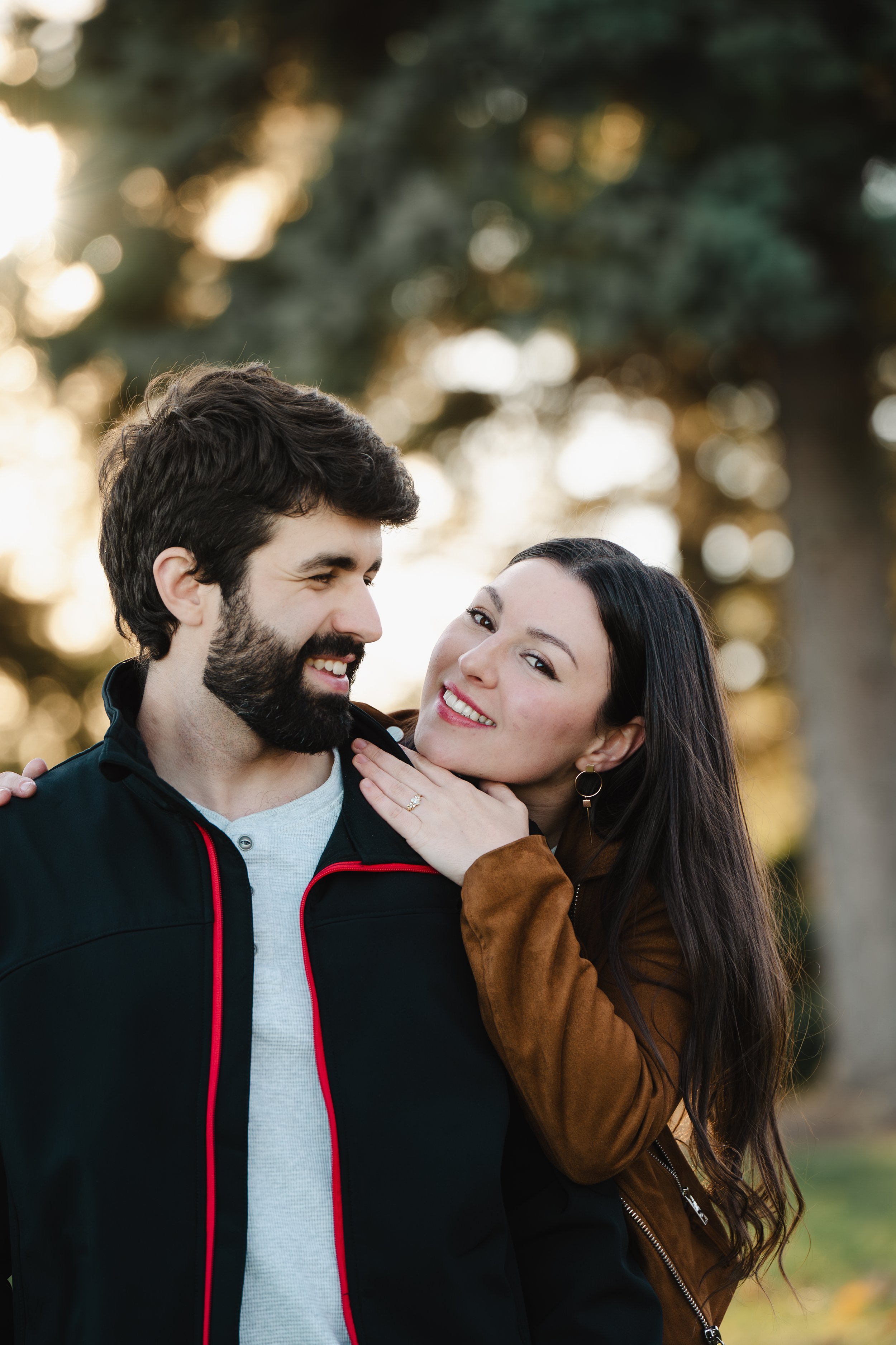 A couple outdoors with woman smiling and hugging man
