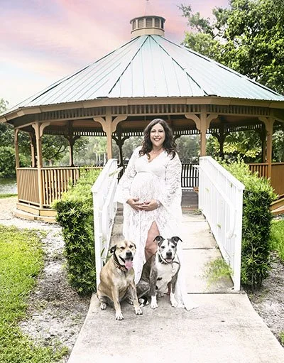 maternity outdoor photography with a gazebo in background and posed with two dogs
