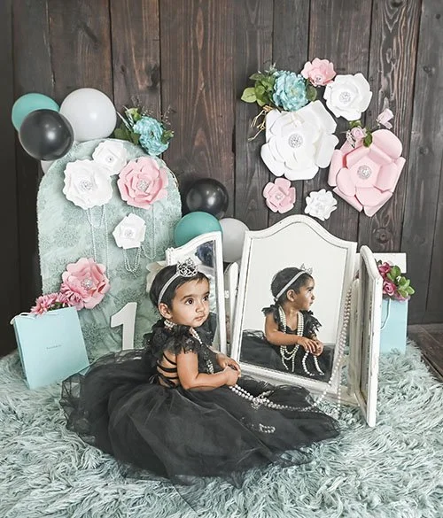 1st birthday girl looking in mirror wearing pearls