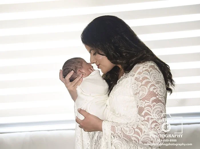 lifestyle newborn photographer mom wearing white lace dress nose to nose with newborn baby boy