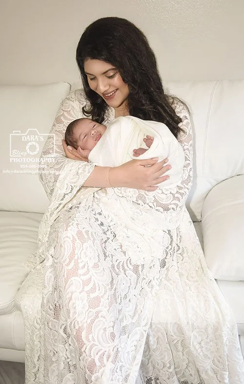 Fort Lauderdale in. home newborn photographer mom sitting on couch holding newborn baby boy
