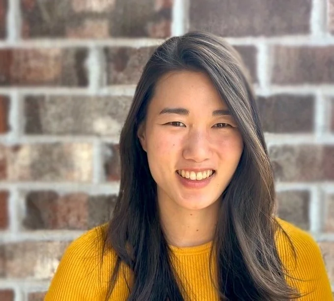 Danielle Lee smiling in front of a brick wall.