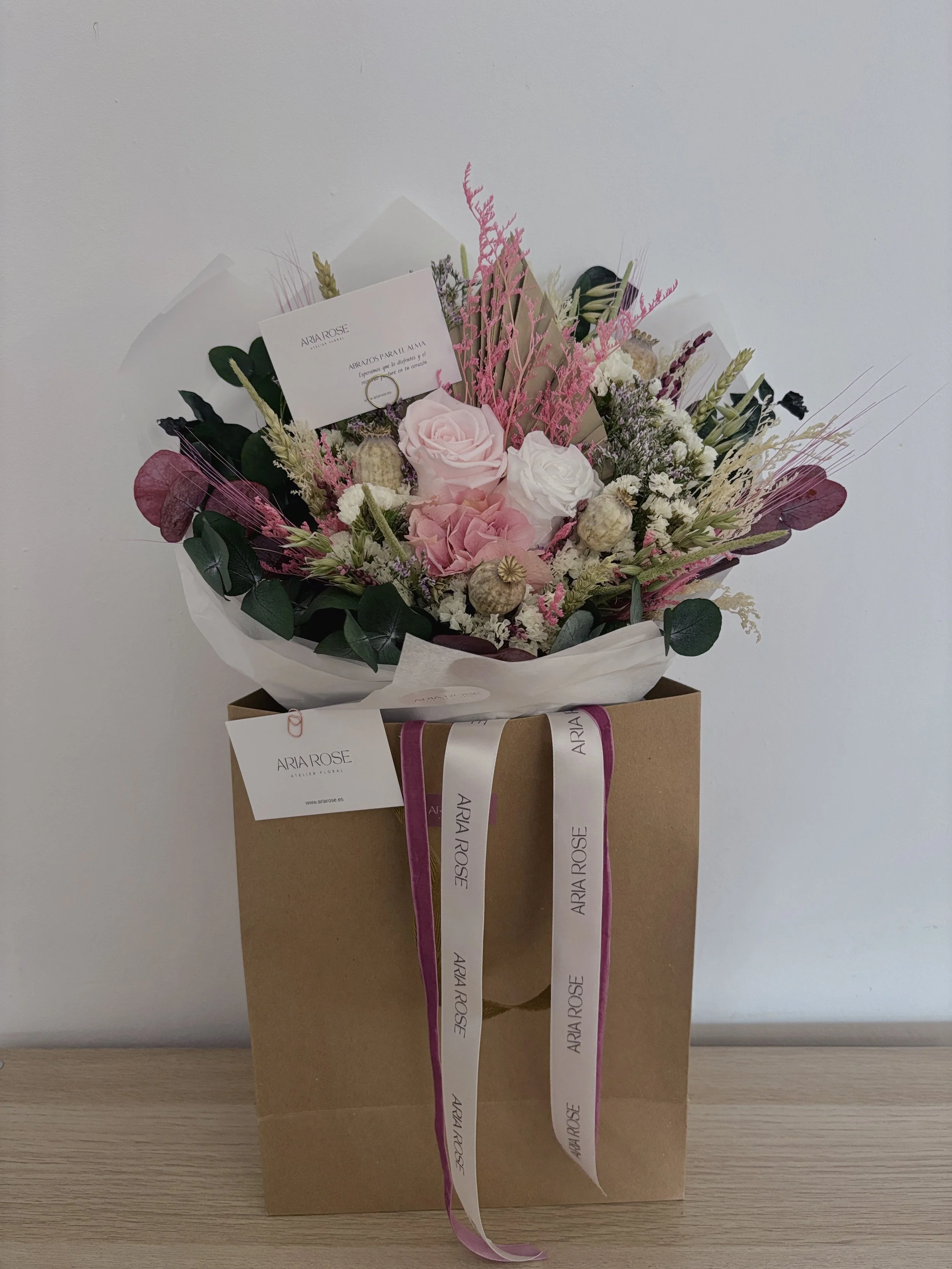 Ramo de flores en caja de regalo con etiquetas y cinta con el nombre 'ARIA ROSE'.