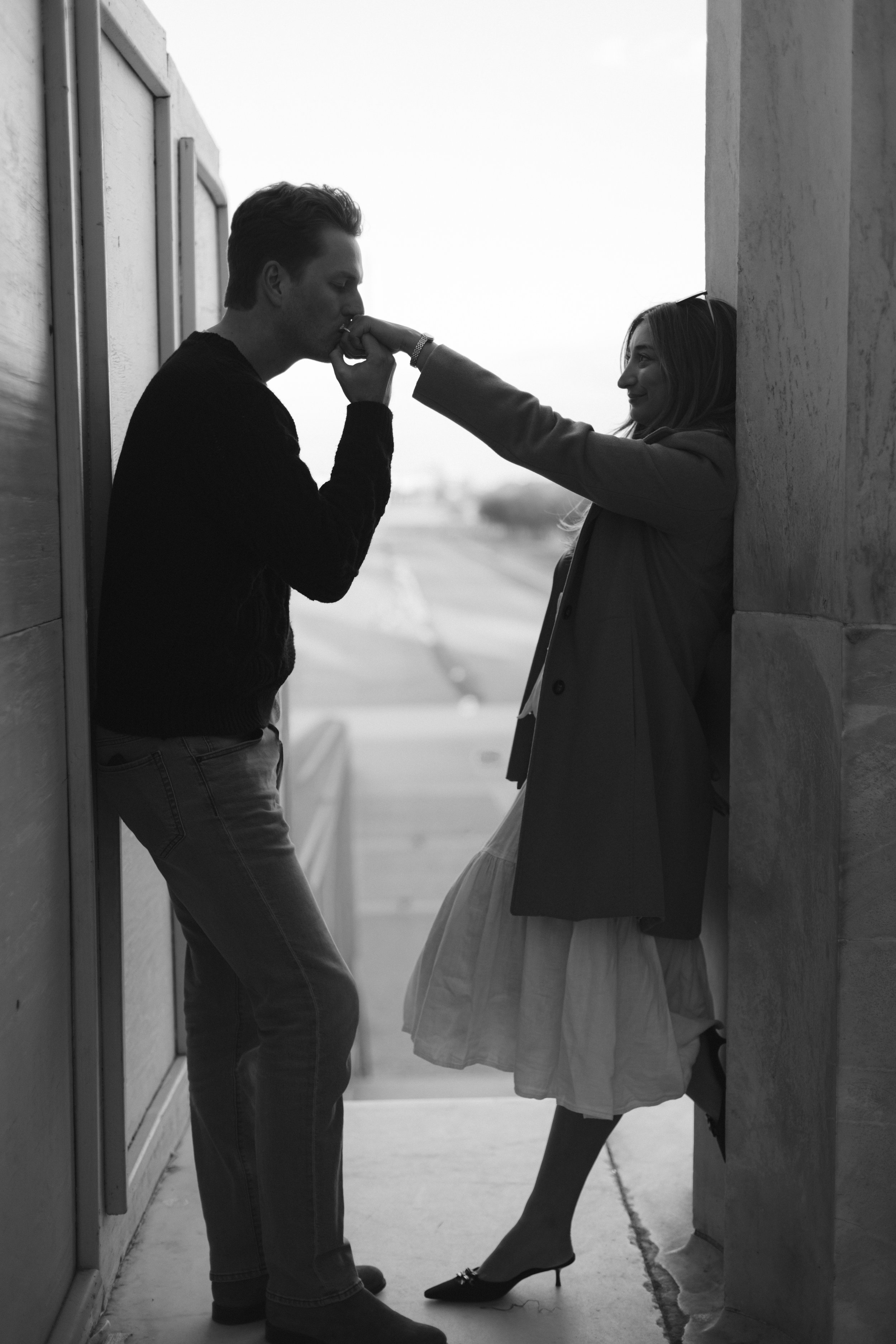 Groom kisses bride’s hand in doorway, intimate gesture by documentary wedding photographer