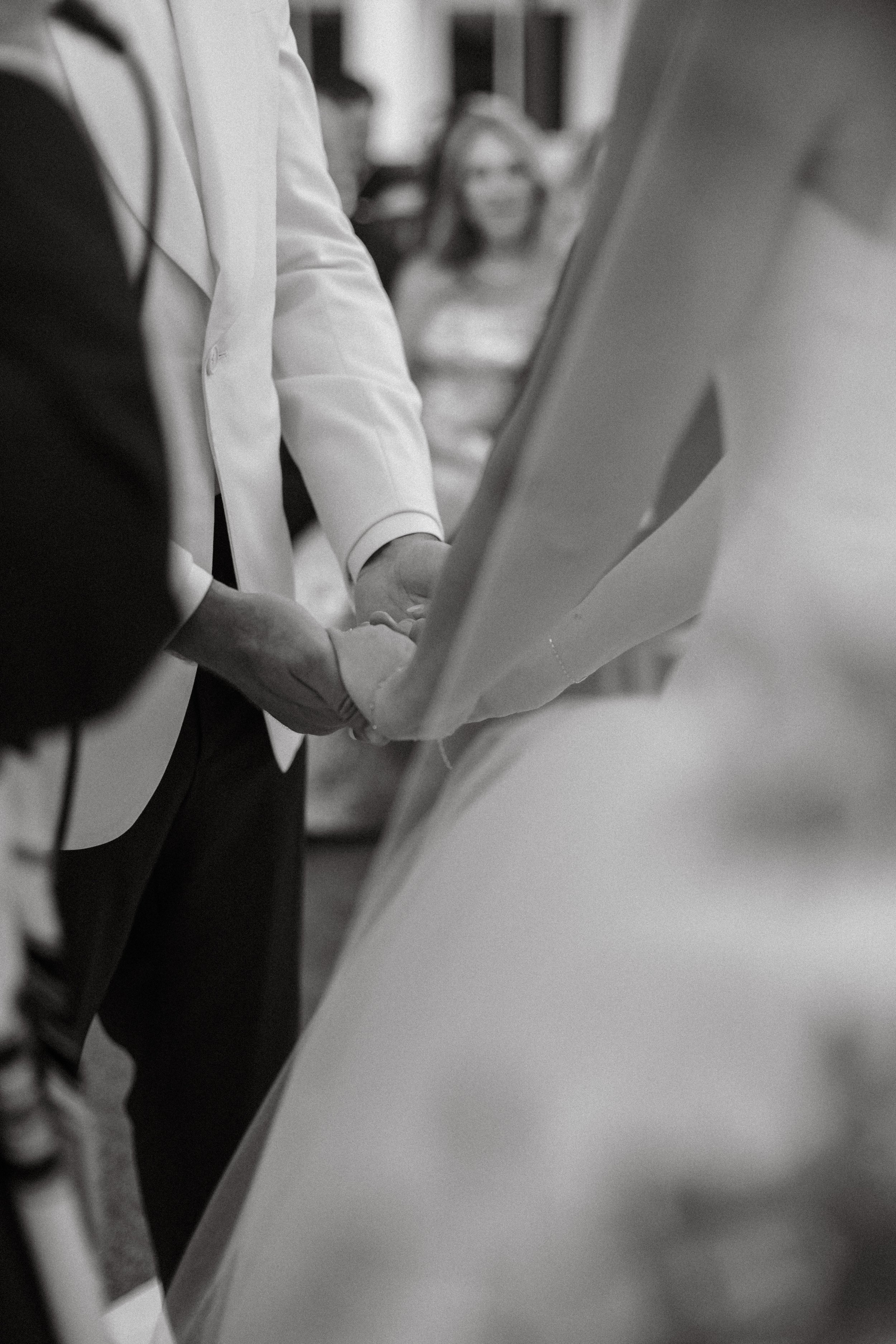 Groom reaches for bride’s hand, black and white documentary style wedding photography