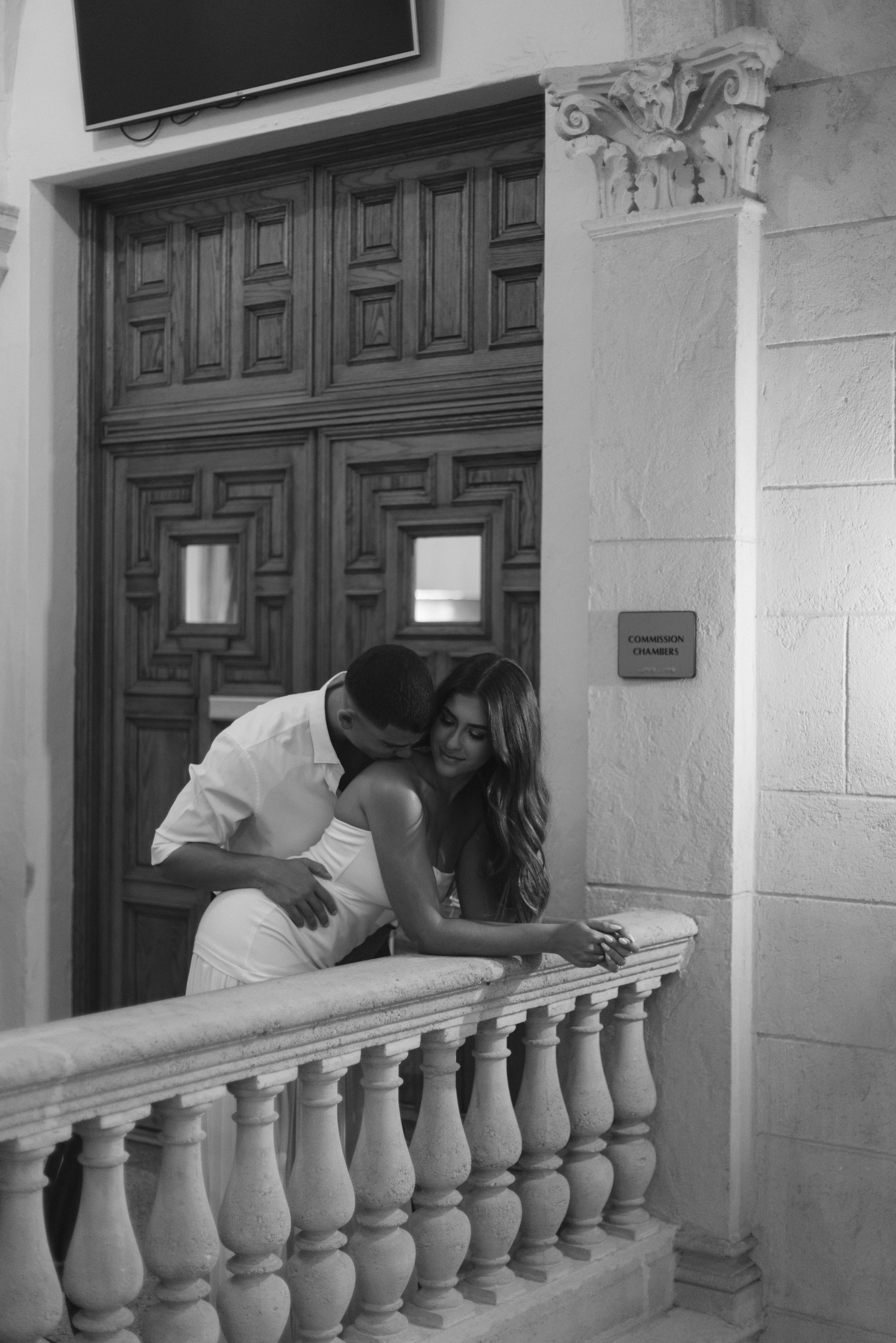 Groom hugs bride on stone balcony, quiet moment in documentary style wedding photography