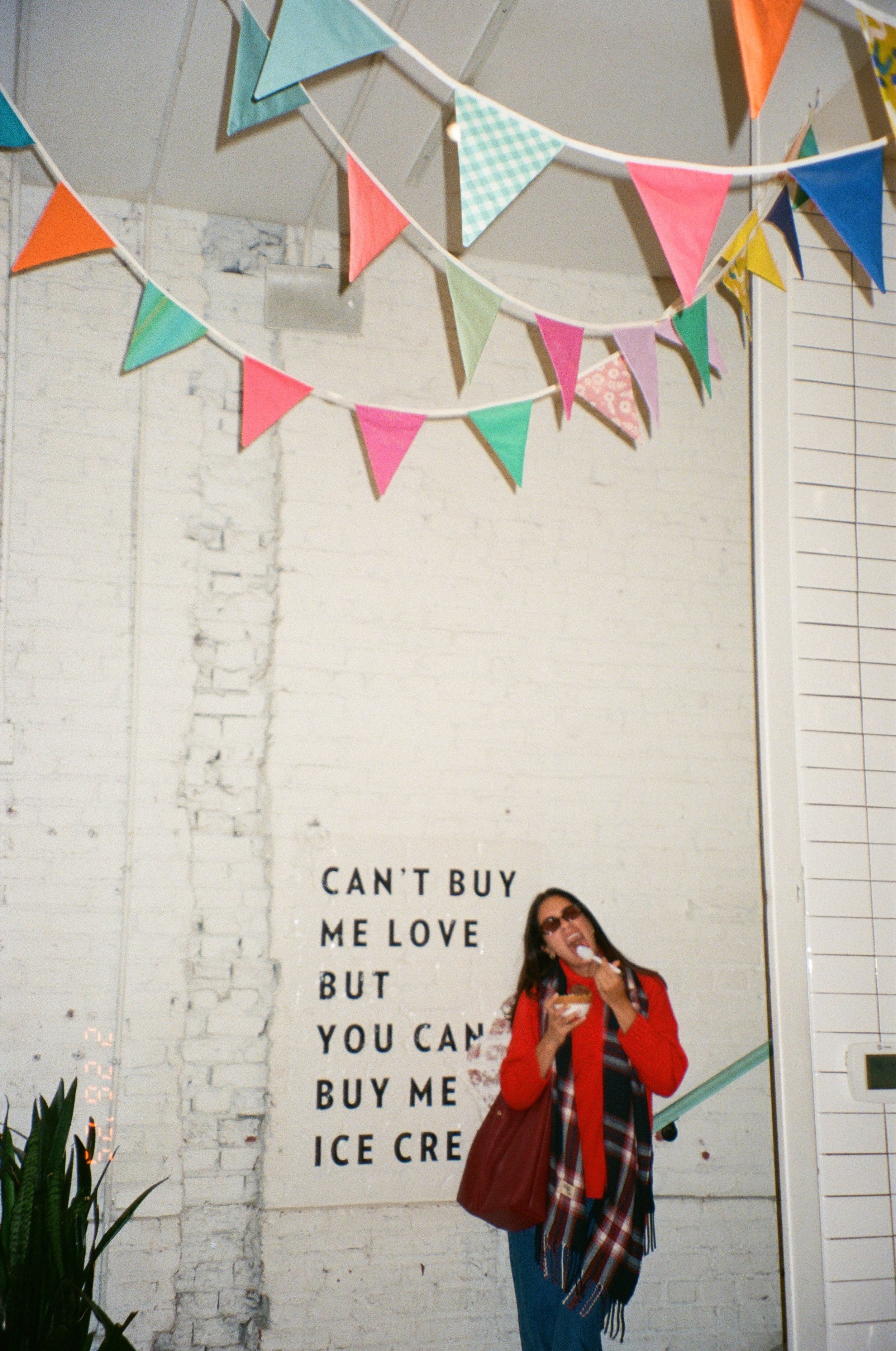 Woman standing by mural and bunting, a playful take on candid wedding photography