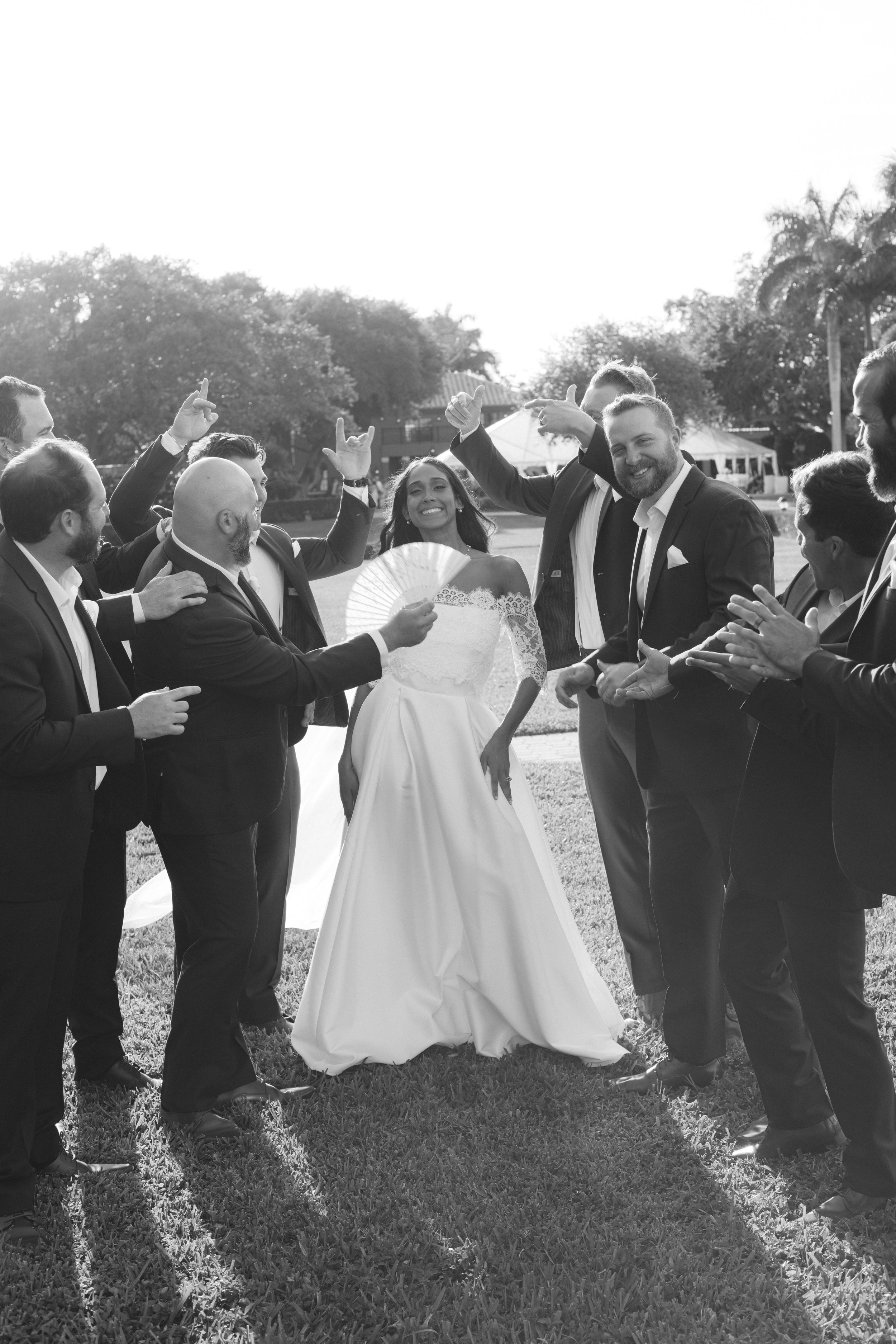 Bride laughing surrounded by groomsmen, real wedding moment by documentary wedding photographer