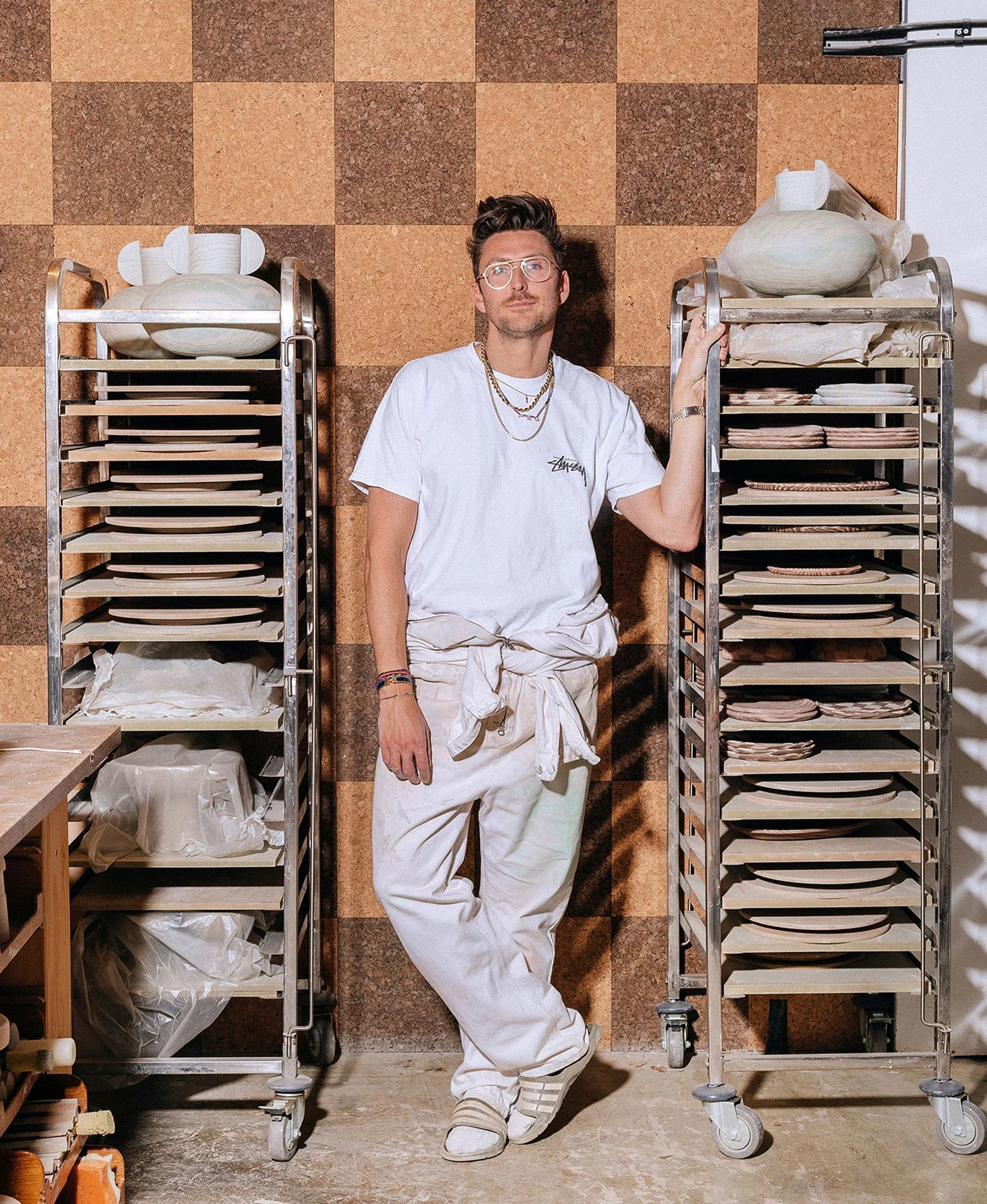 Man standing next to shelves of drying ceramics