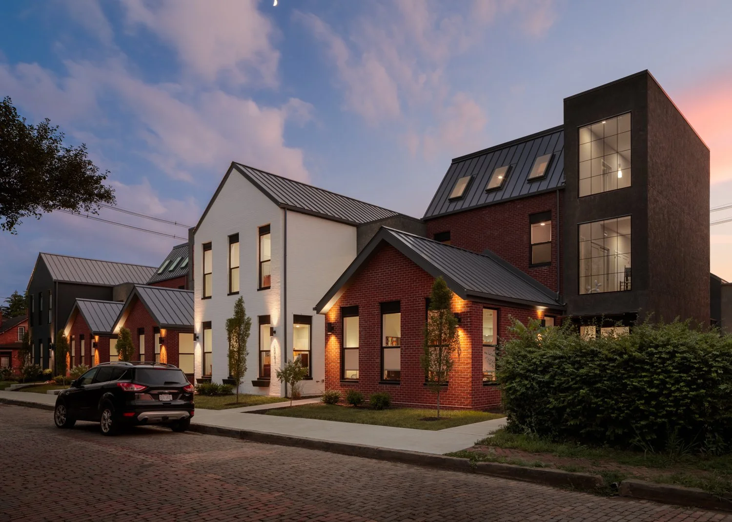 Twilight view of a serene residential street in Columbus, Ohio, featuring a row of elegant townhouses with modern design and warm lighting, developed by DEV Partners, highlighting premium real estate investment opportunities.