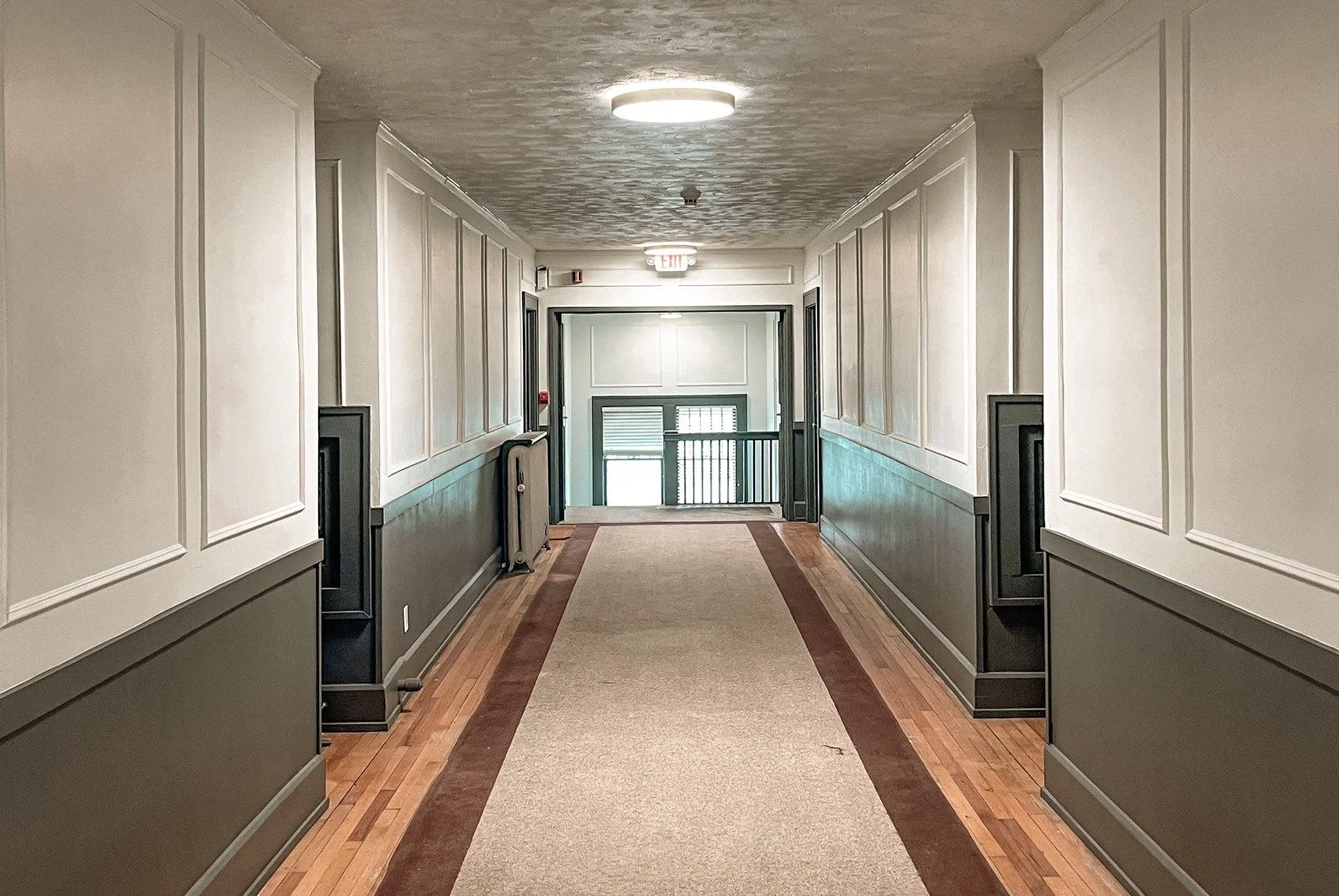 Elegant hallway inside a multi-family property in Des Moines, Iowa, part of a passive income rental development by DEV Partners, featuring wainscoting walls and wood flooring, ideal for real estate investment.