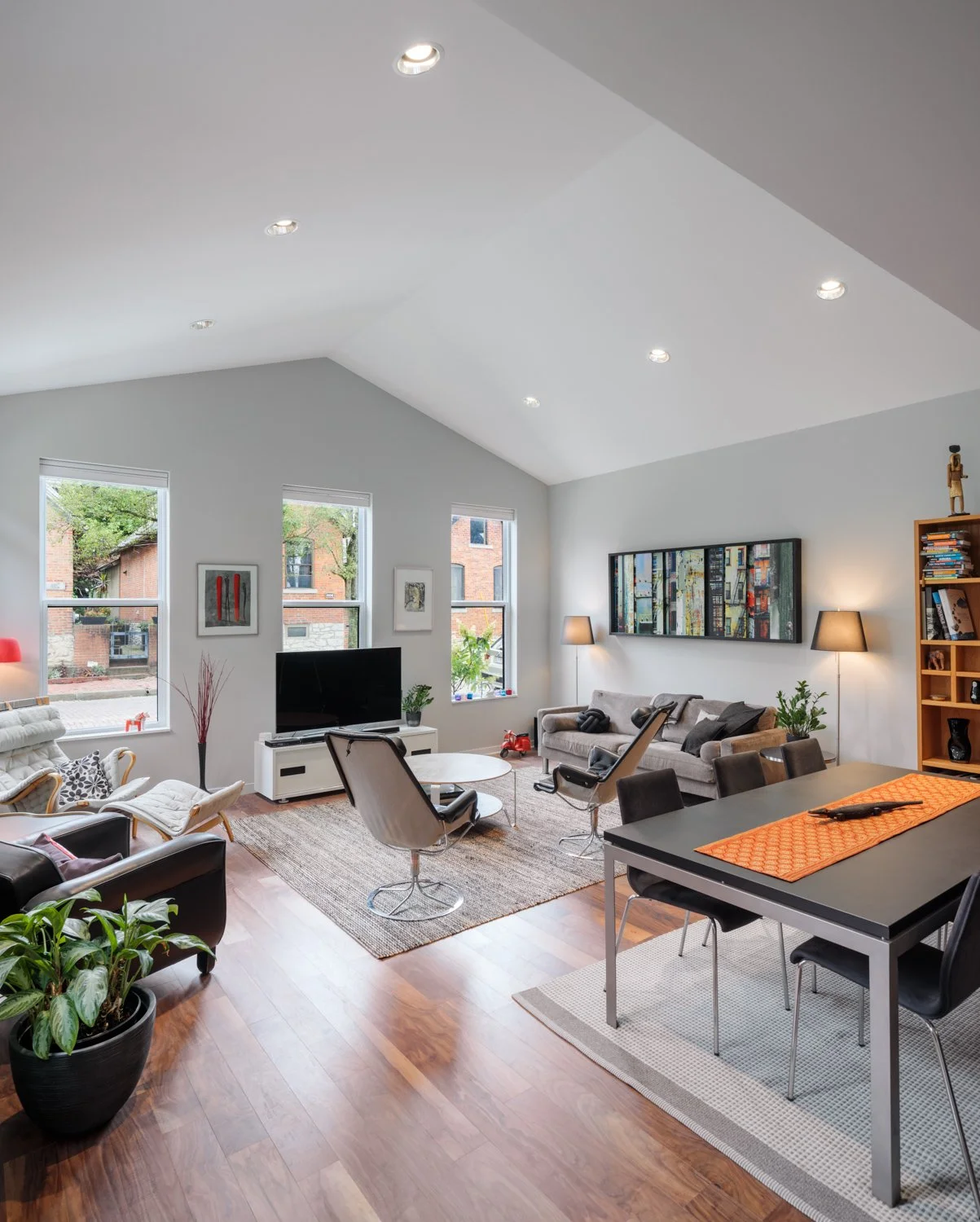 Spacious and modern living room in a Columbus, Ohio real estate development by DEV Partners, featuring vaulted ceilings, large windows, contemporary furniture, and a stylish entertainment area, ideal for those looking to invest in upscale urban livin