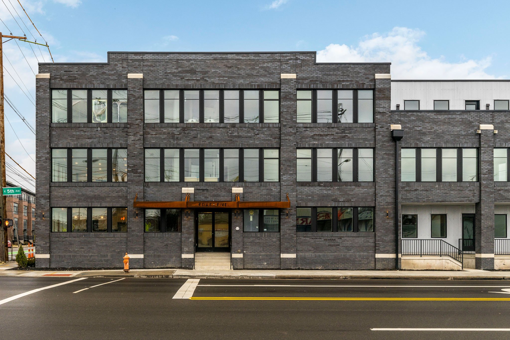 Modern multi-family residential building in Columbus, Ohio, featuring a sleek gray brick facade and large windows, developed by DEV Partners for passive income rentals, ideal for real estate investment opportunities.