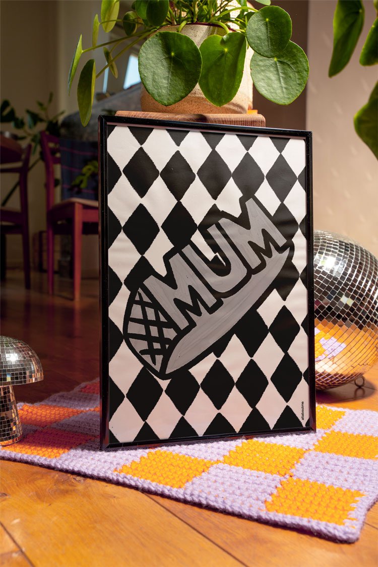 A bold silver Mum ring illustration on a black-and-white diamond-patterned background, blending nostalgia with a modern pop-art twist.