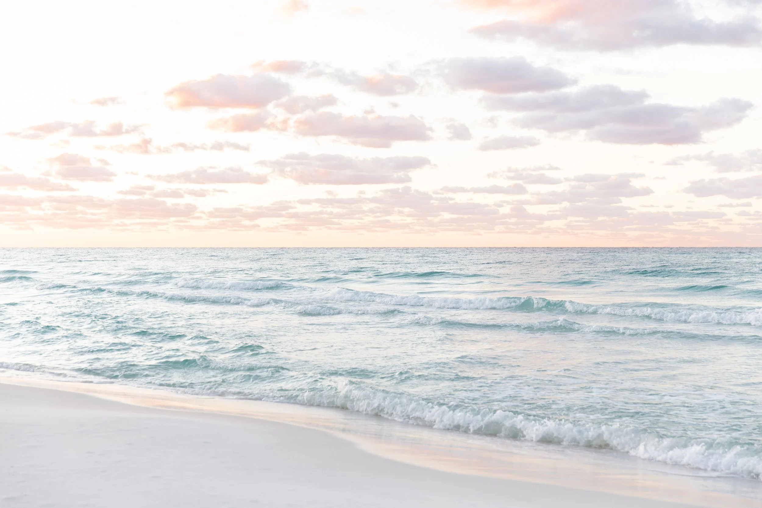 Serene beach scene with gentle waves and a colorful cloudy sky at sunset