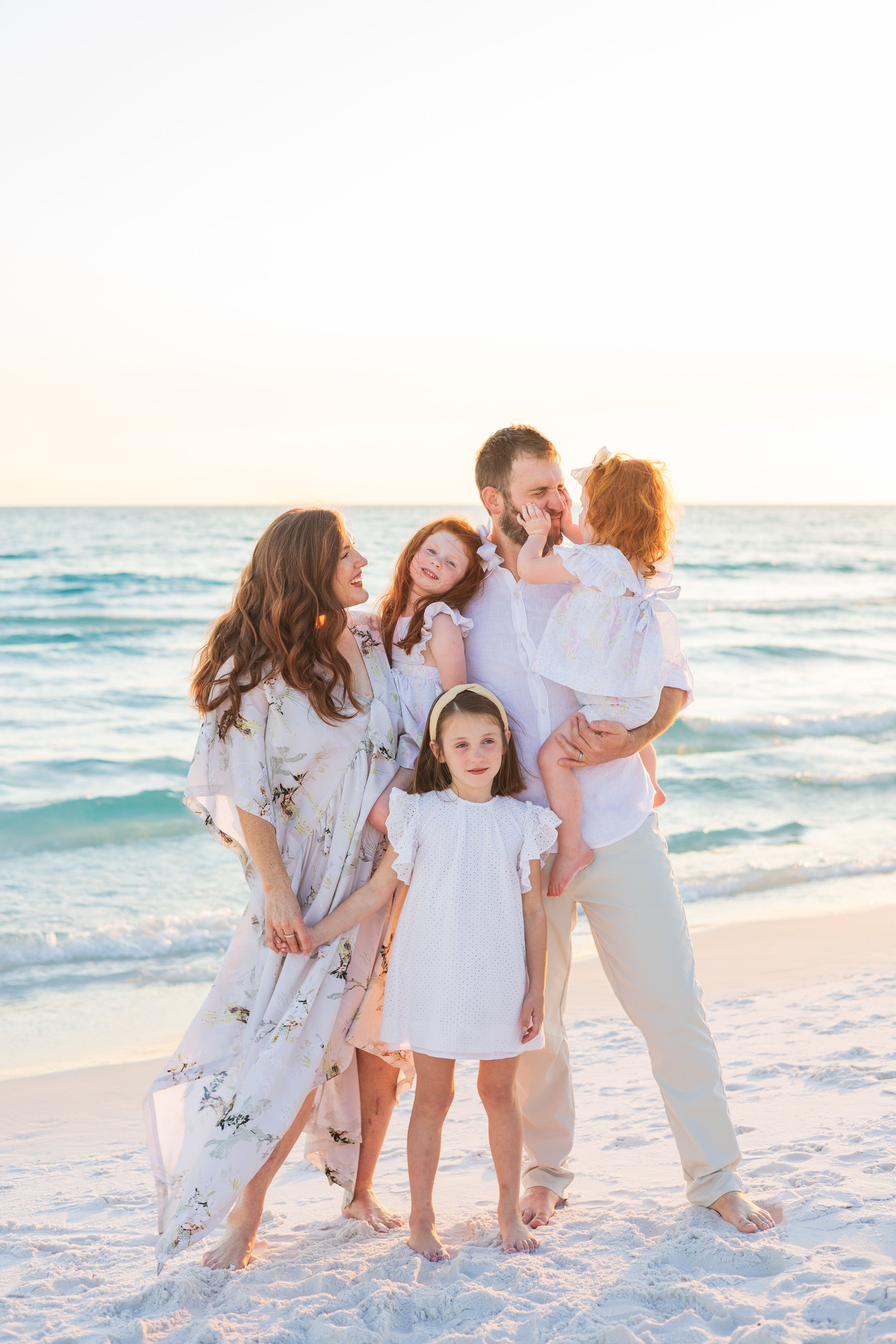 Family with three children at the beach during sunset, smiling and playing.