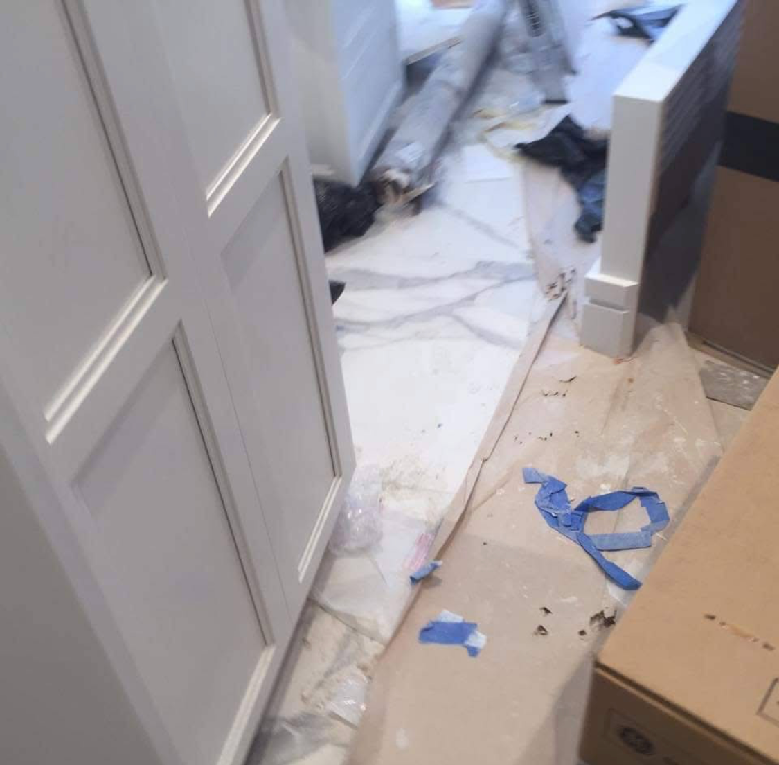 A construction or renovation area with a partially installed tile floor, scattered debris, and tools or materials in the space.
