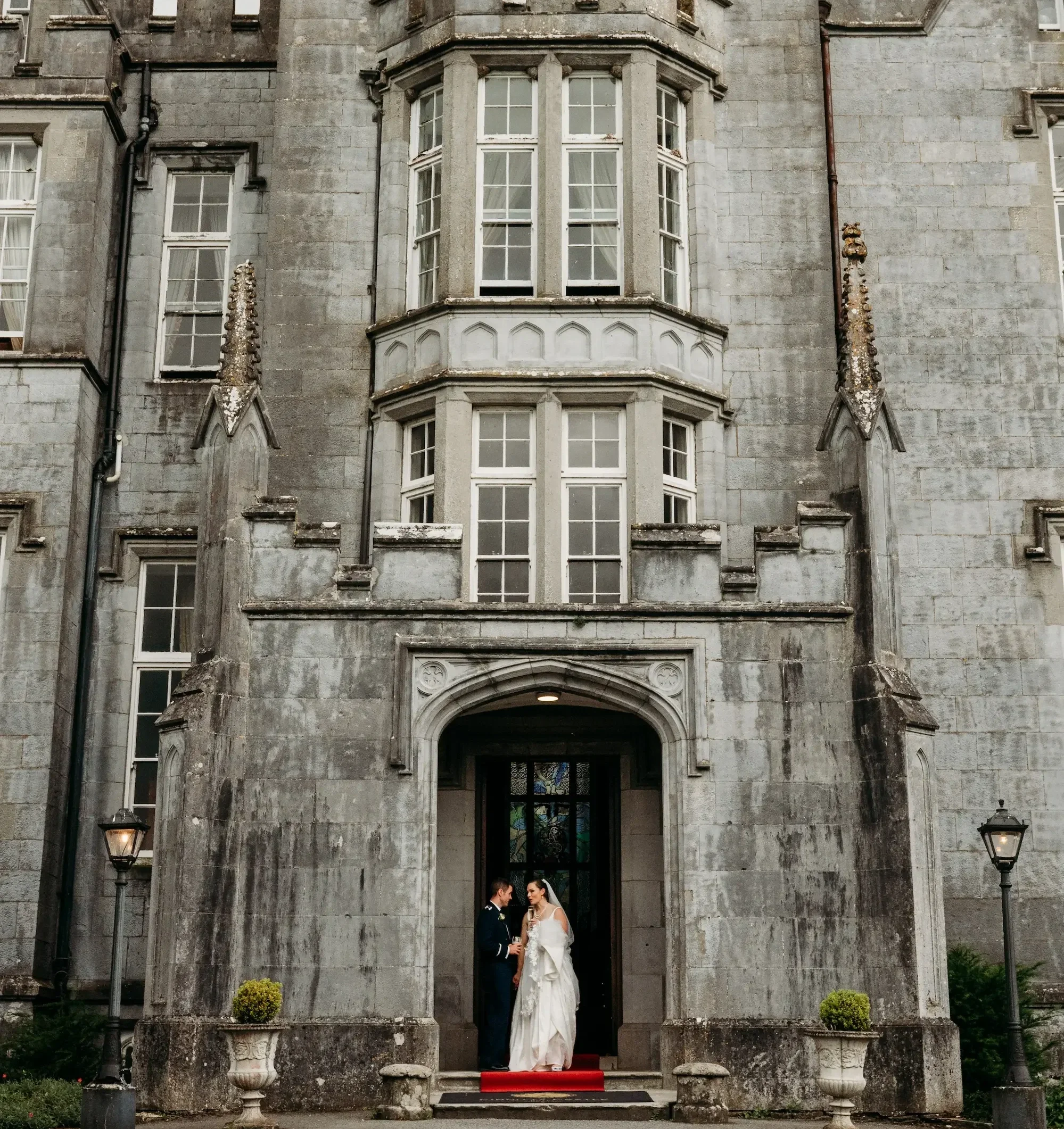 Bride and groom standing together in front of Kinnitty Castle's stone entrance