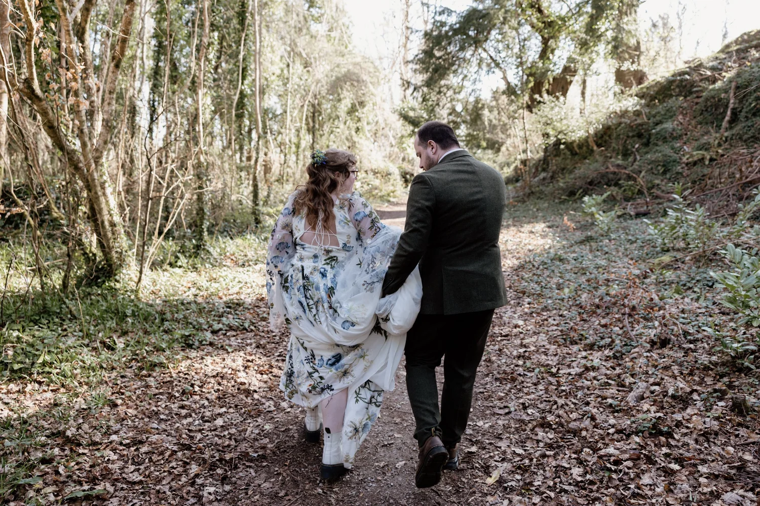 Kelli and Ethan walking hand-in-hand through a wooded trail in Killarney National Park