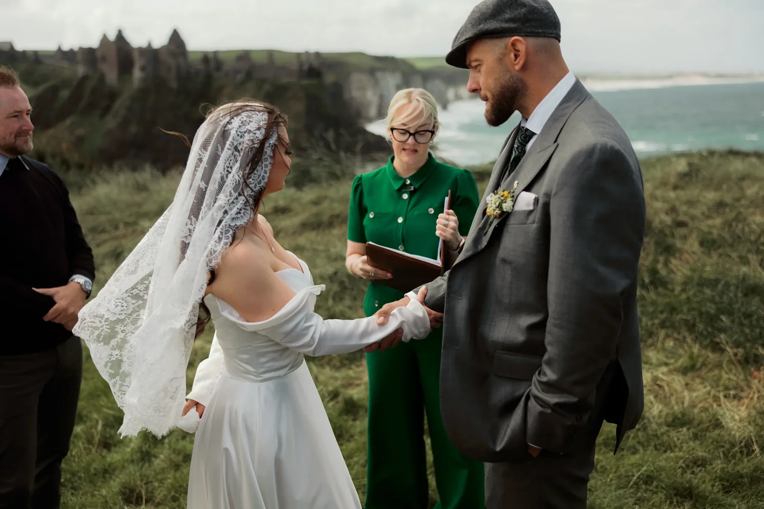 Michelle and Bradley holding hands during a wedding ceremony outdoors near the coast