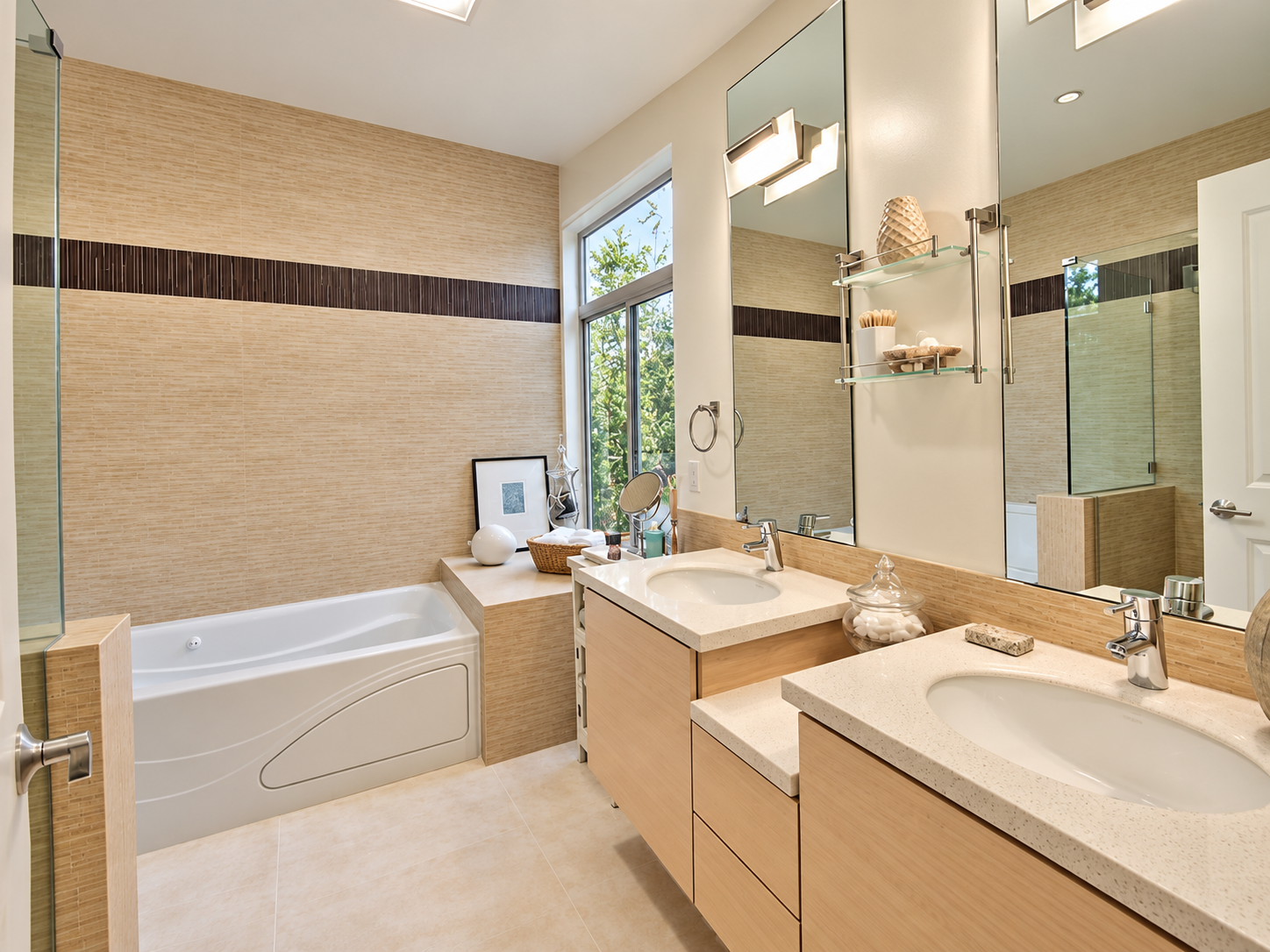 Bathroom with light tile, a double vanity, and a bathtub.
