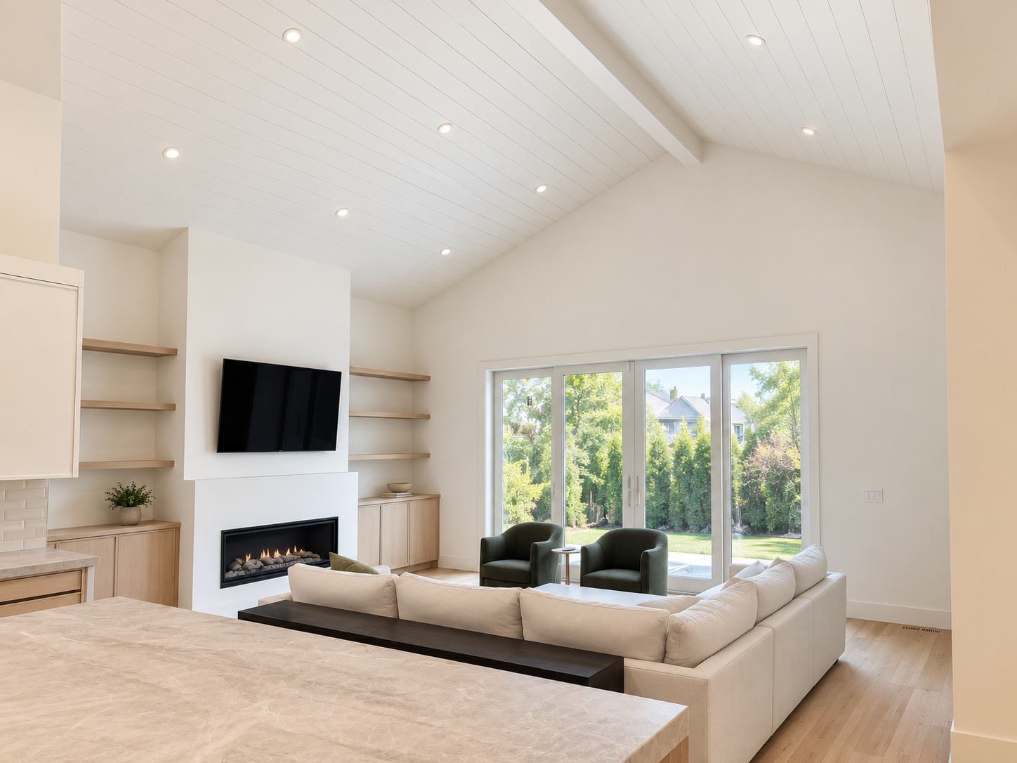 Vaulted living room with a fireplace, built-in cabinetry, and large windows.