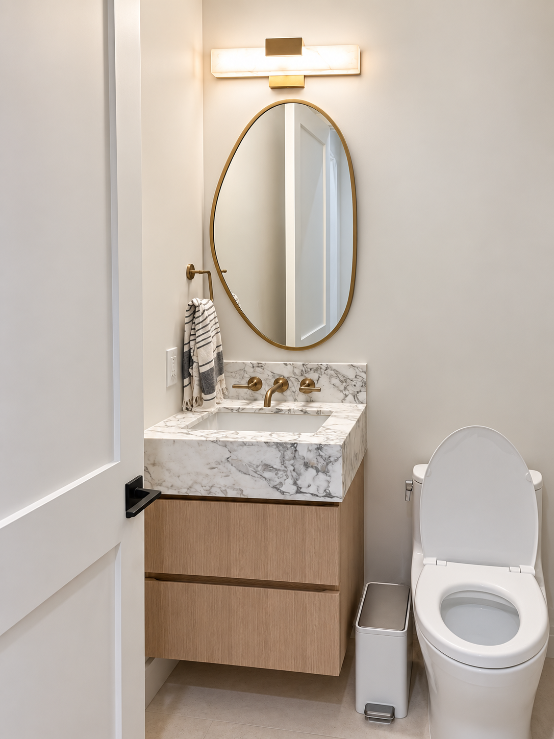 Powder room with a wood vanity, stone countertop, and arched mirror.