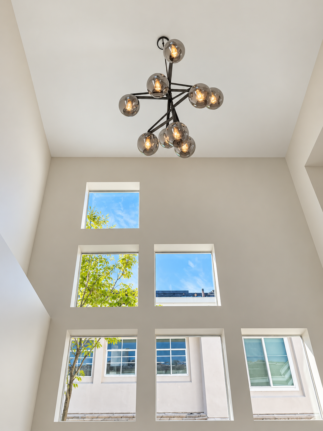 Sculptural chandelier and stacked windows in the double-height entry.