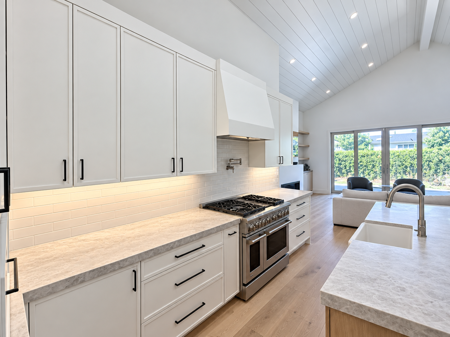 Galley kitchen with white cabinetry, under-cabinet lighting, and wood floors.