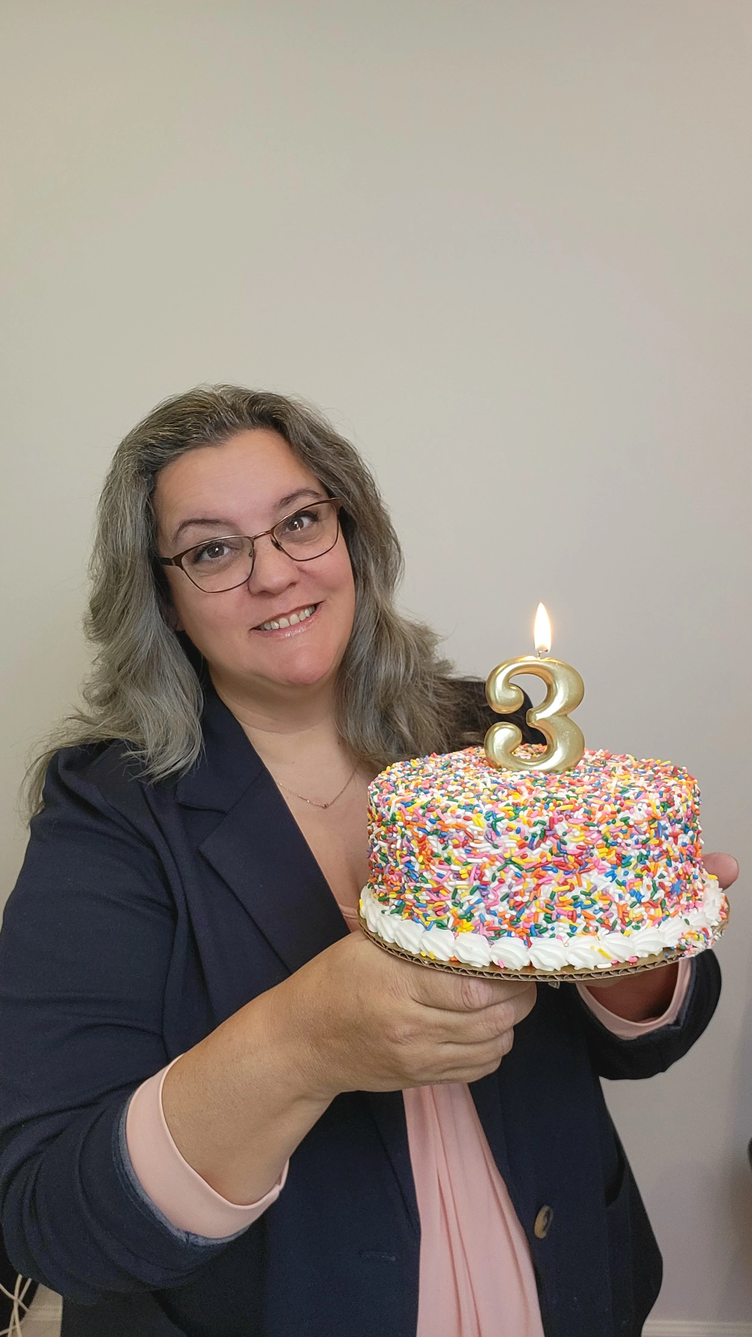 Doreen Laskiewicz holds a birthday cake with a number 3 as the candle