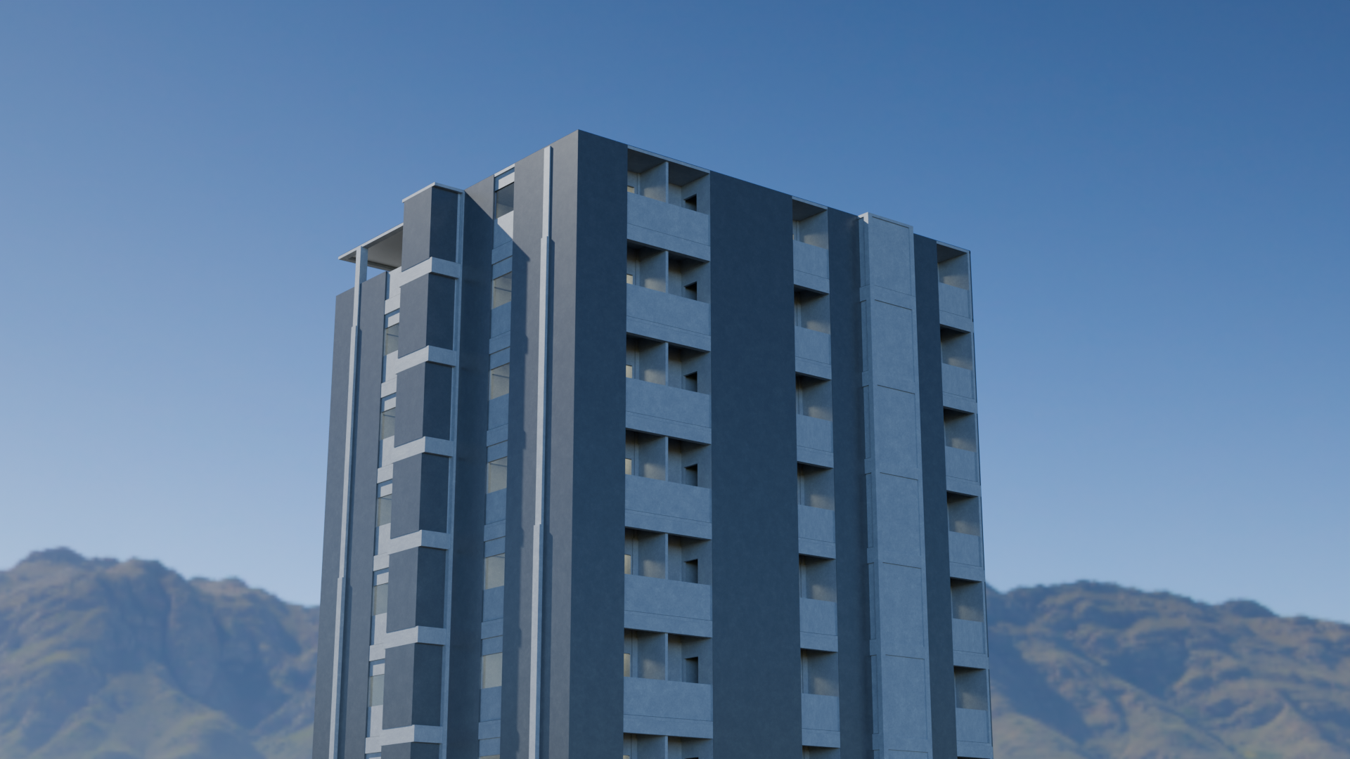 A tall modern gray concrete apartment building with multiple balconies, set against a clear blue sky with distant mountains in the background.