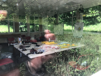 view through a window into an empty art class room, with reflections of grasses on the window glass