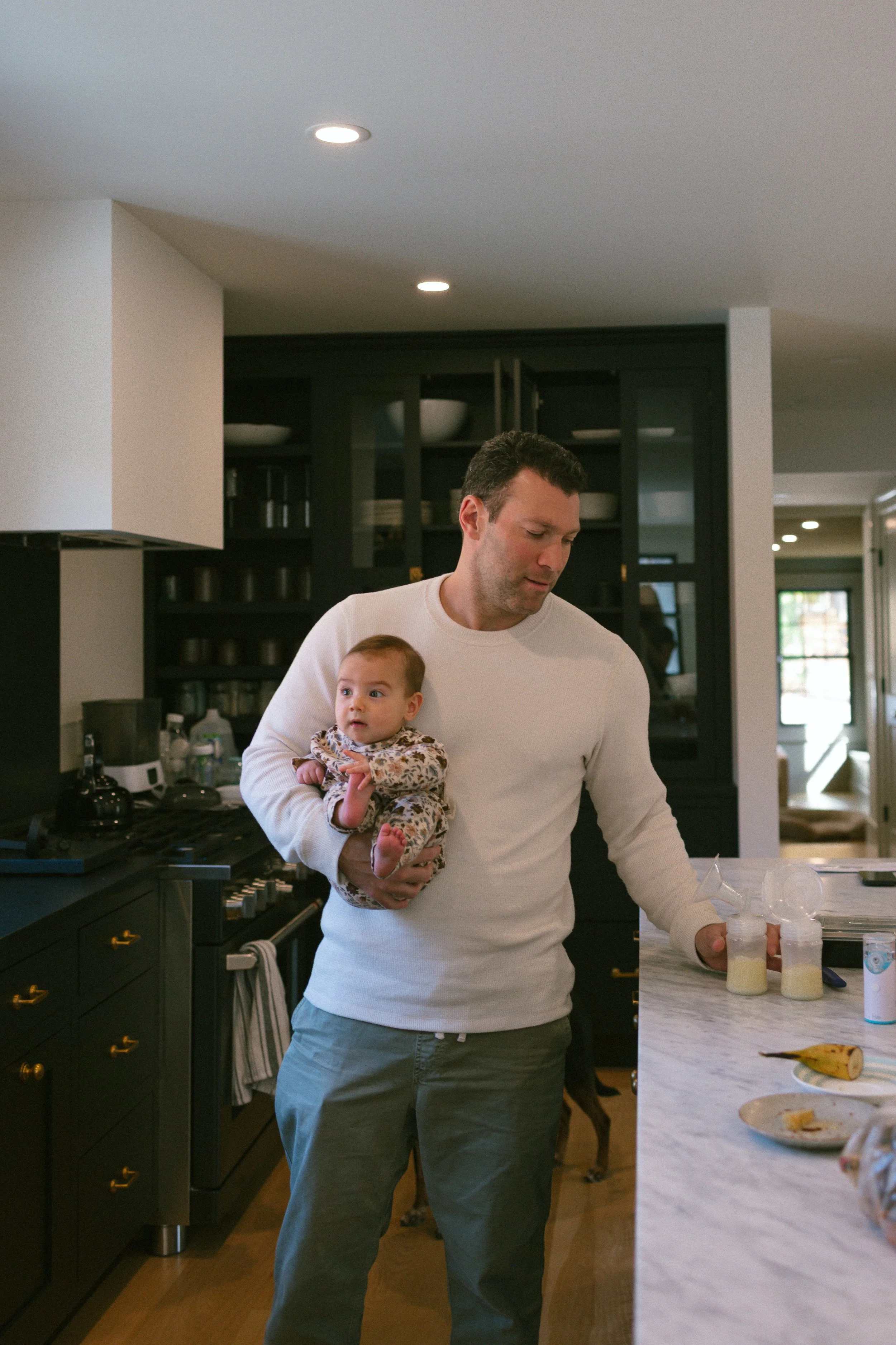 A man holding a baby girl in a kitchen.
