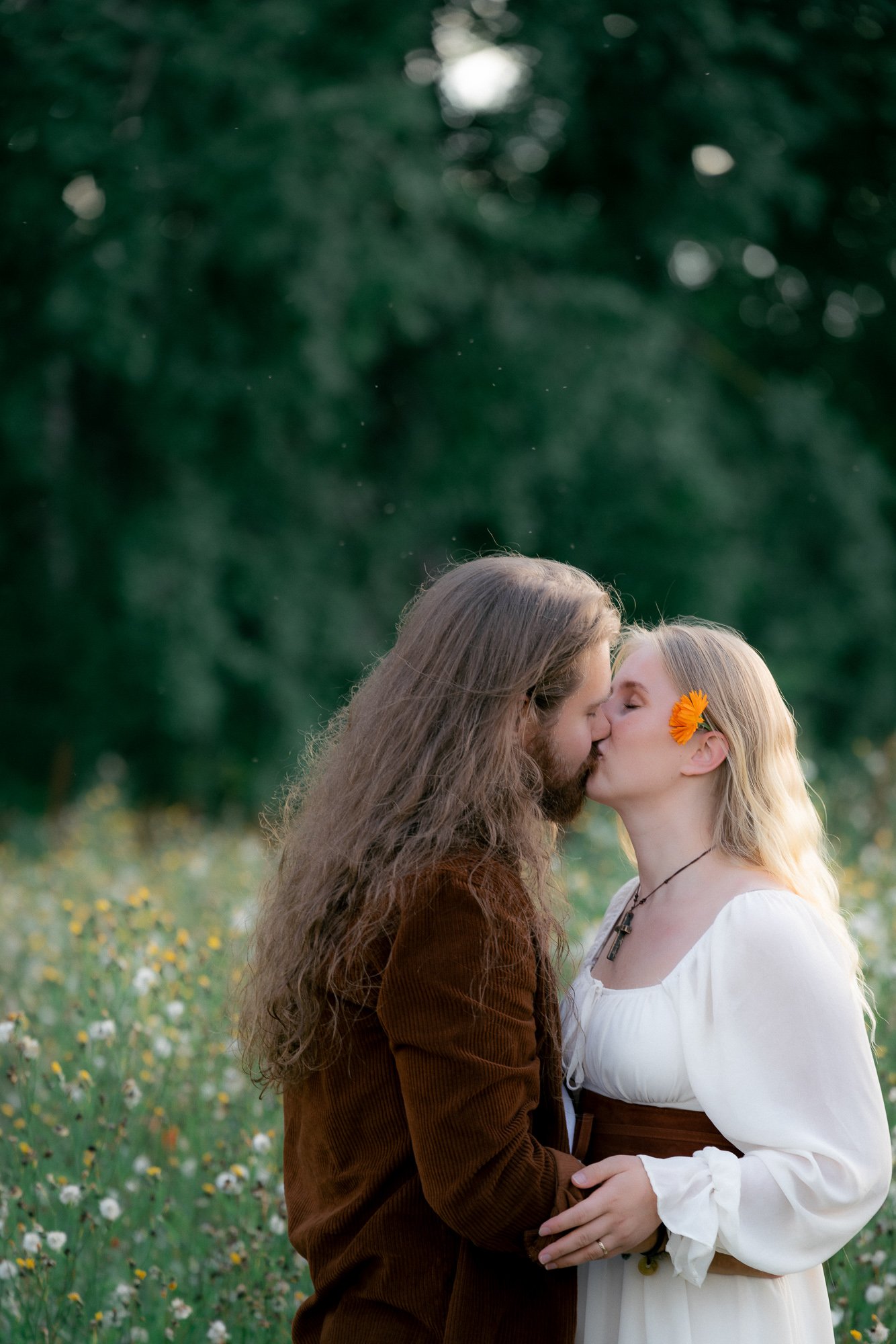 Rento ja dokumentaarinen kihlakuvaus kukkaniityllä, jossa luonto ja miljöön värikkyys korostaa kihlauksen pariskunnan intiimiä romanttista tunnelmaa ja rakkautta.