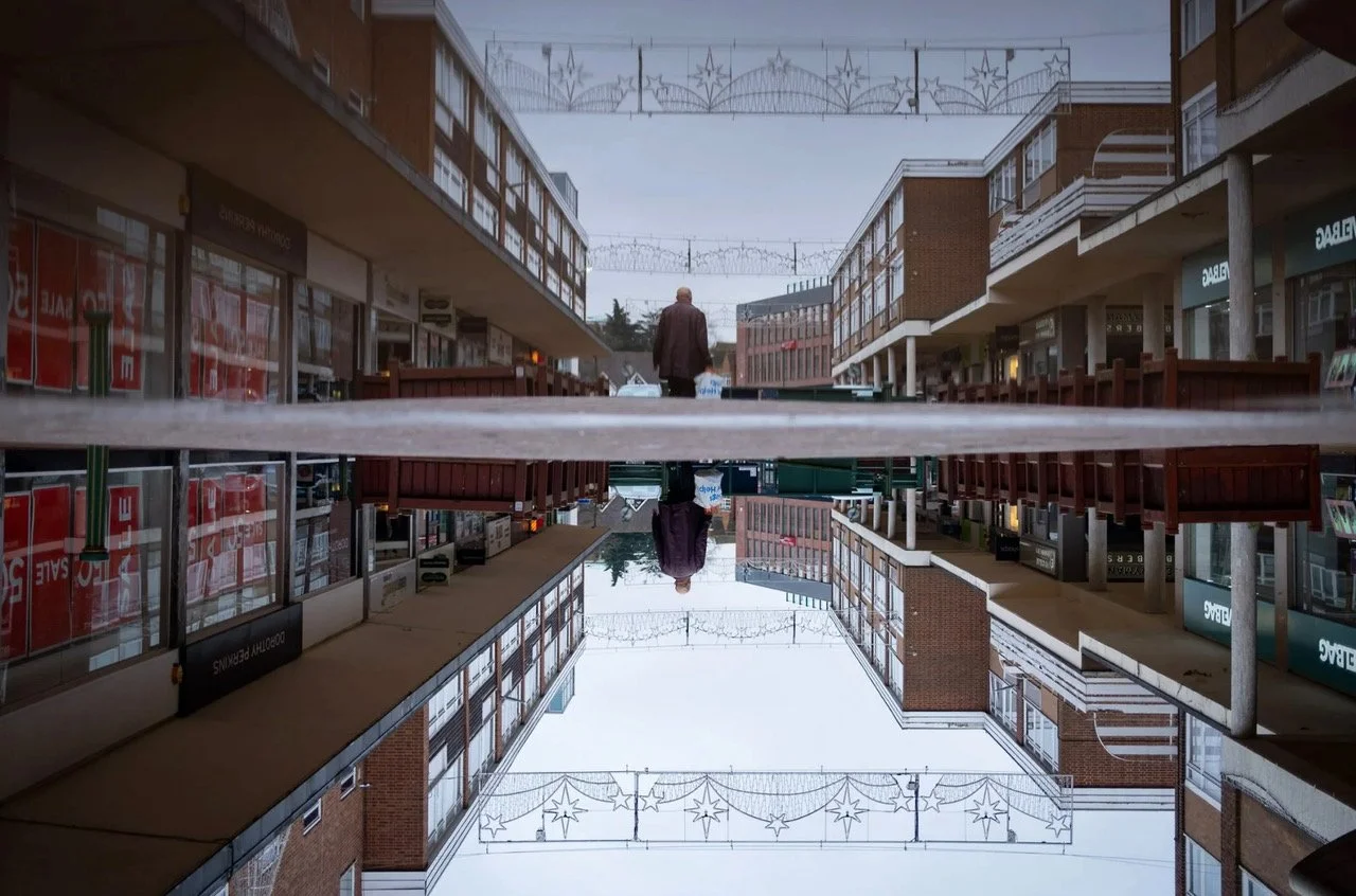 An image of a 1960's or 1970's shopping street that is some how mirrored. It doesn't quite make sense