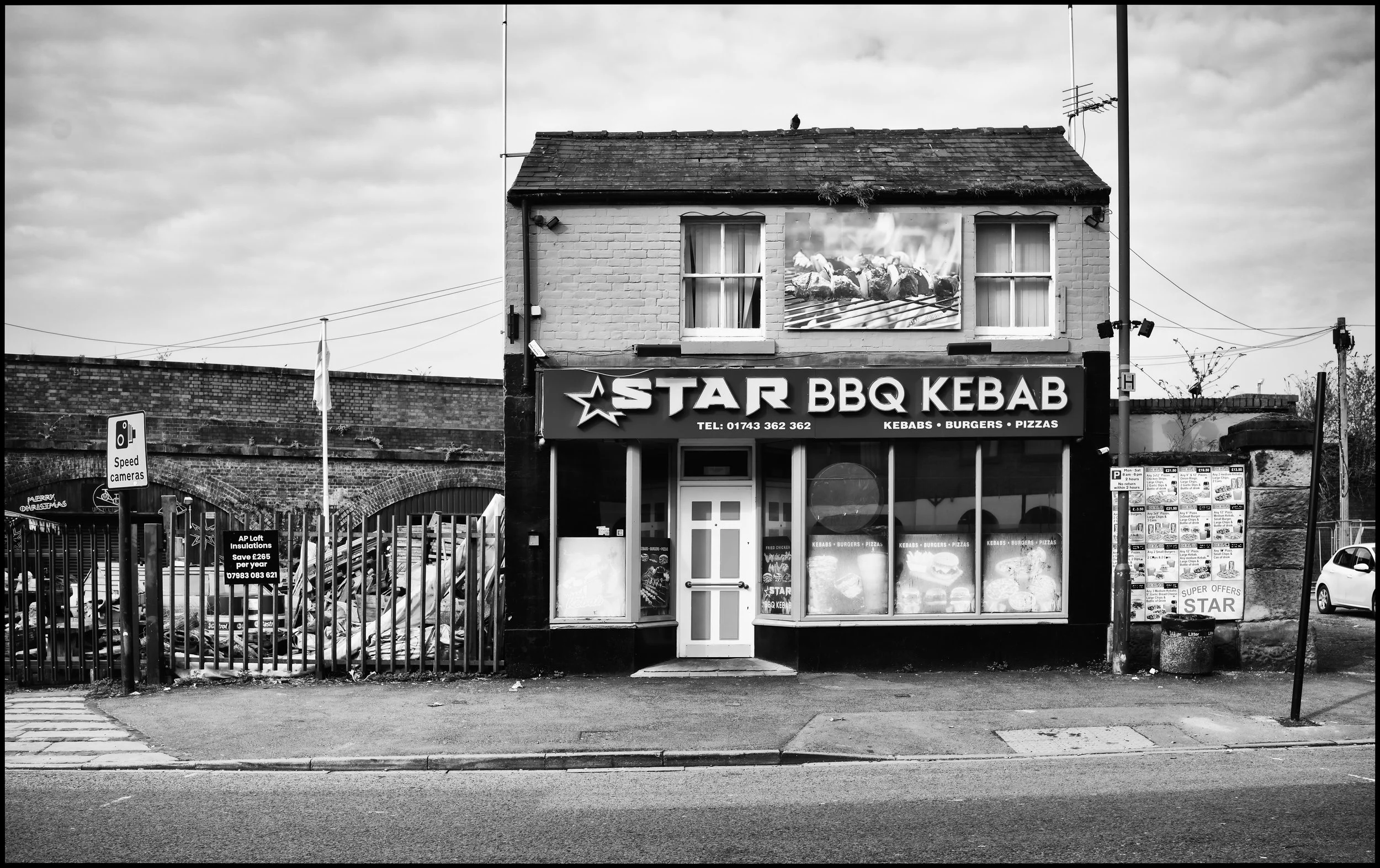 A black and white landscape image of a seemingly Victorian building standing alone in an urban landscape. This contains the Star BBQ Kebab shop