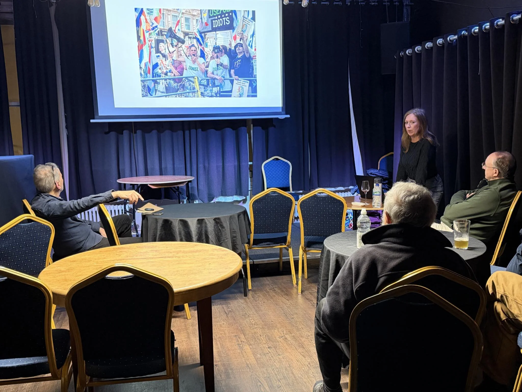 Image of Tracey standing in front of the screen talking about an image; an image showing a far right protest she documented.