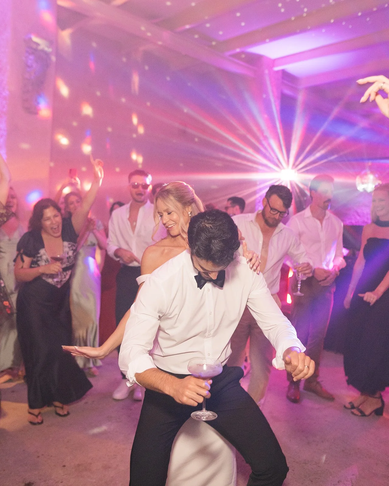 People dancing and having fun at a lively party or celebration with colorful lighting and disco effects.