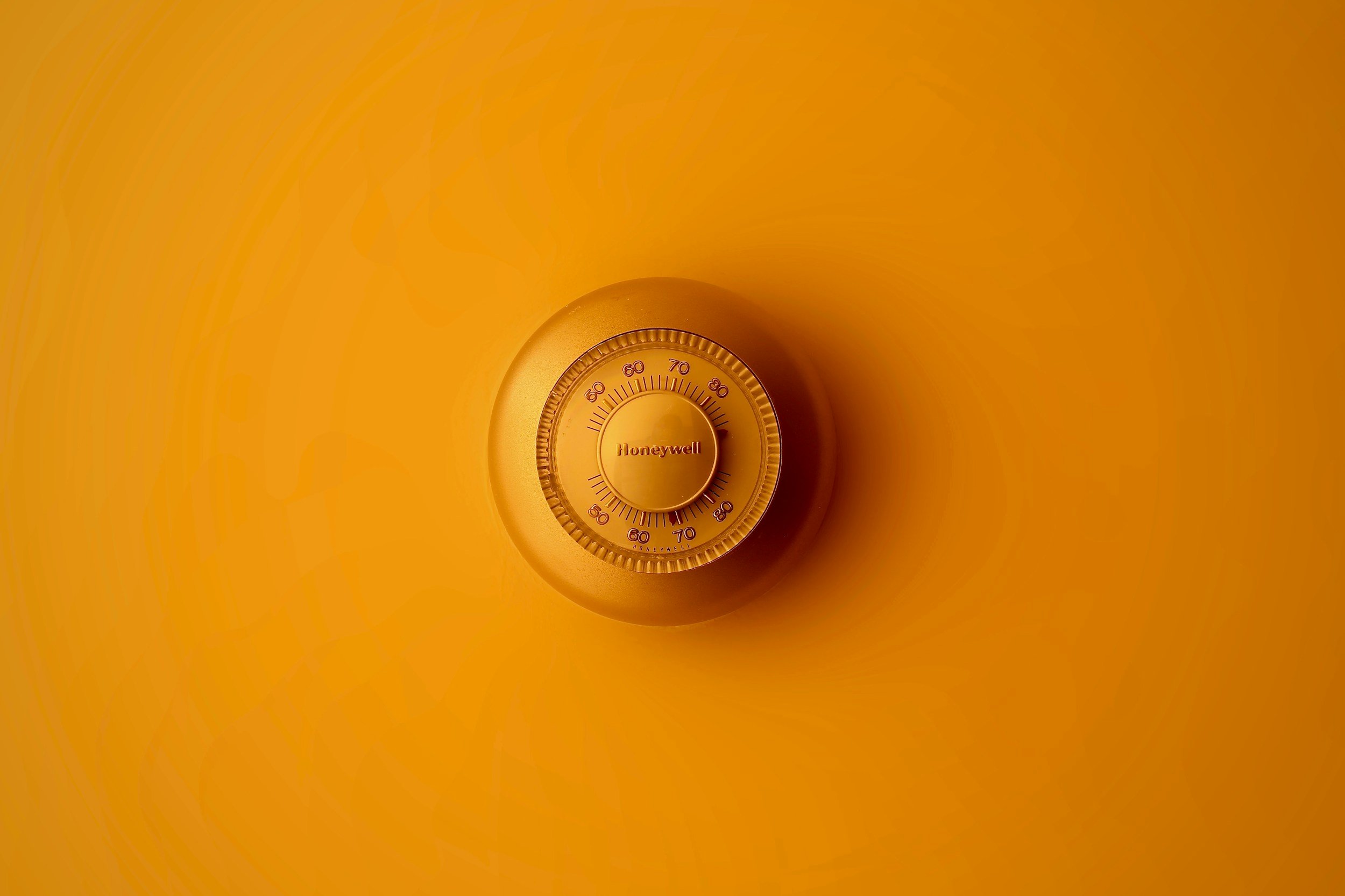A yellow Honeywell combination safe dial lock on a matching yellow background.