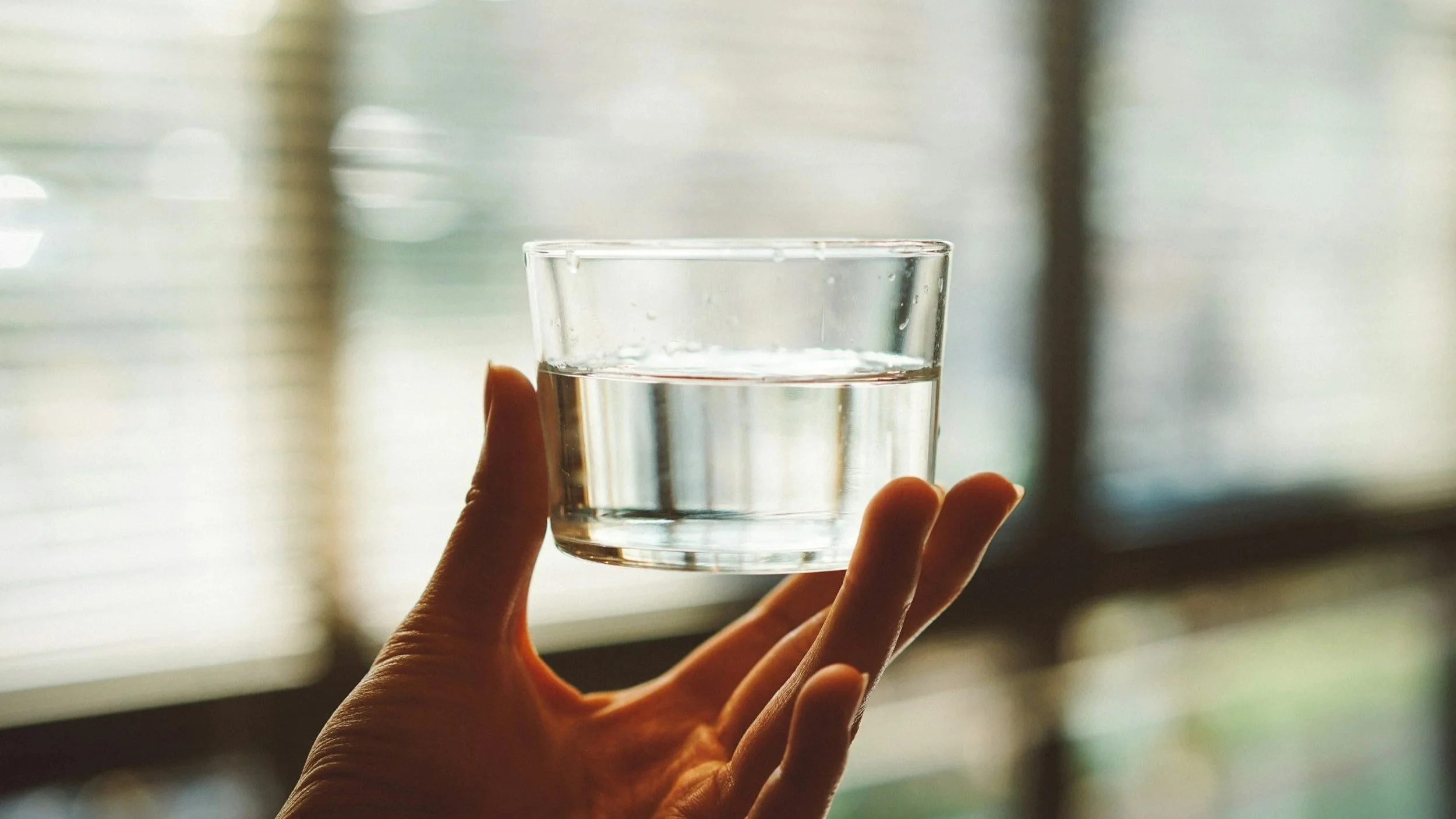 a hand holding a small glass of water