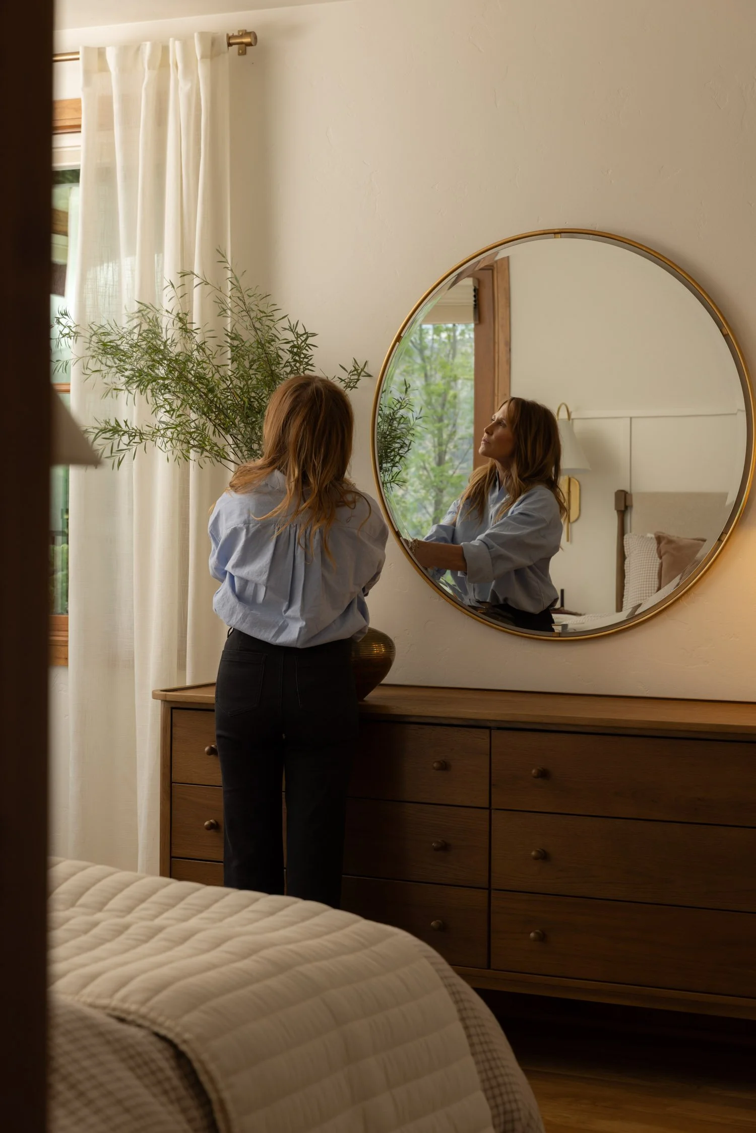 Cozy Vail bedroom with textured bedding, wooden dresser, and gold mirror by interior designer Krista Weisman