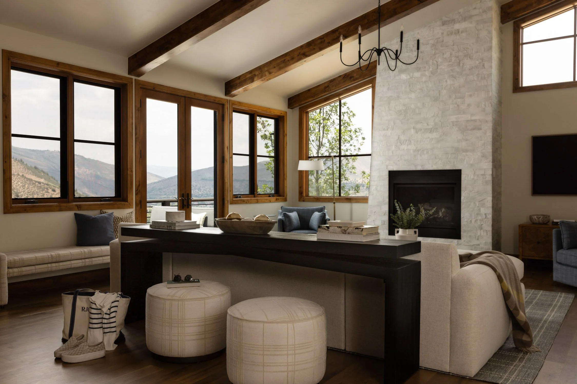 Heirloom decor in a cozy Vail living room with stone fireplace, exposed beams, and mountain views, by Intentional Design Company.