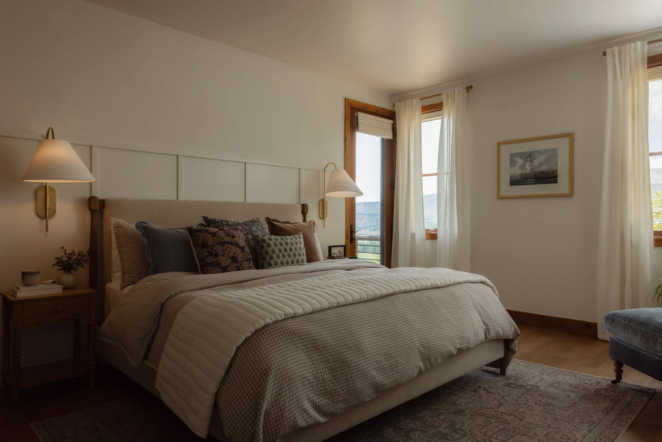 Cozy Vail bedroom with textured pillows, white millwork, and and wall sconces by interior designer Krista Weisman of Intentional Design Co.