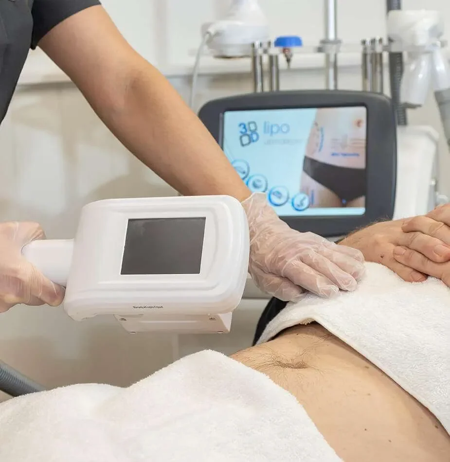 A person receiving a skin treatment with a handheld device, with a screen displaying information and a medical setting in the background.