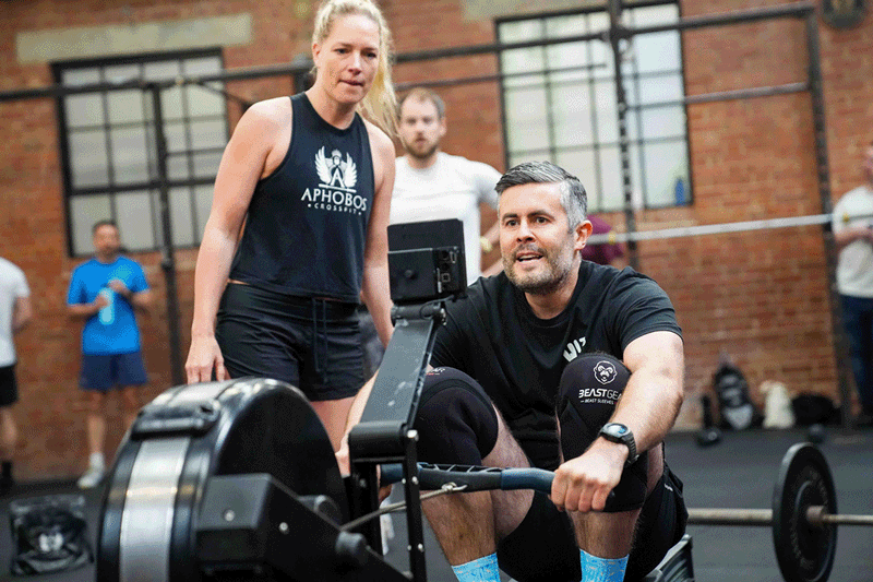Two people at a rowing machine in a gym