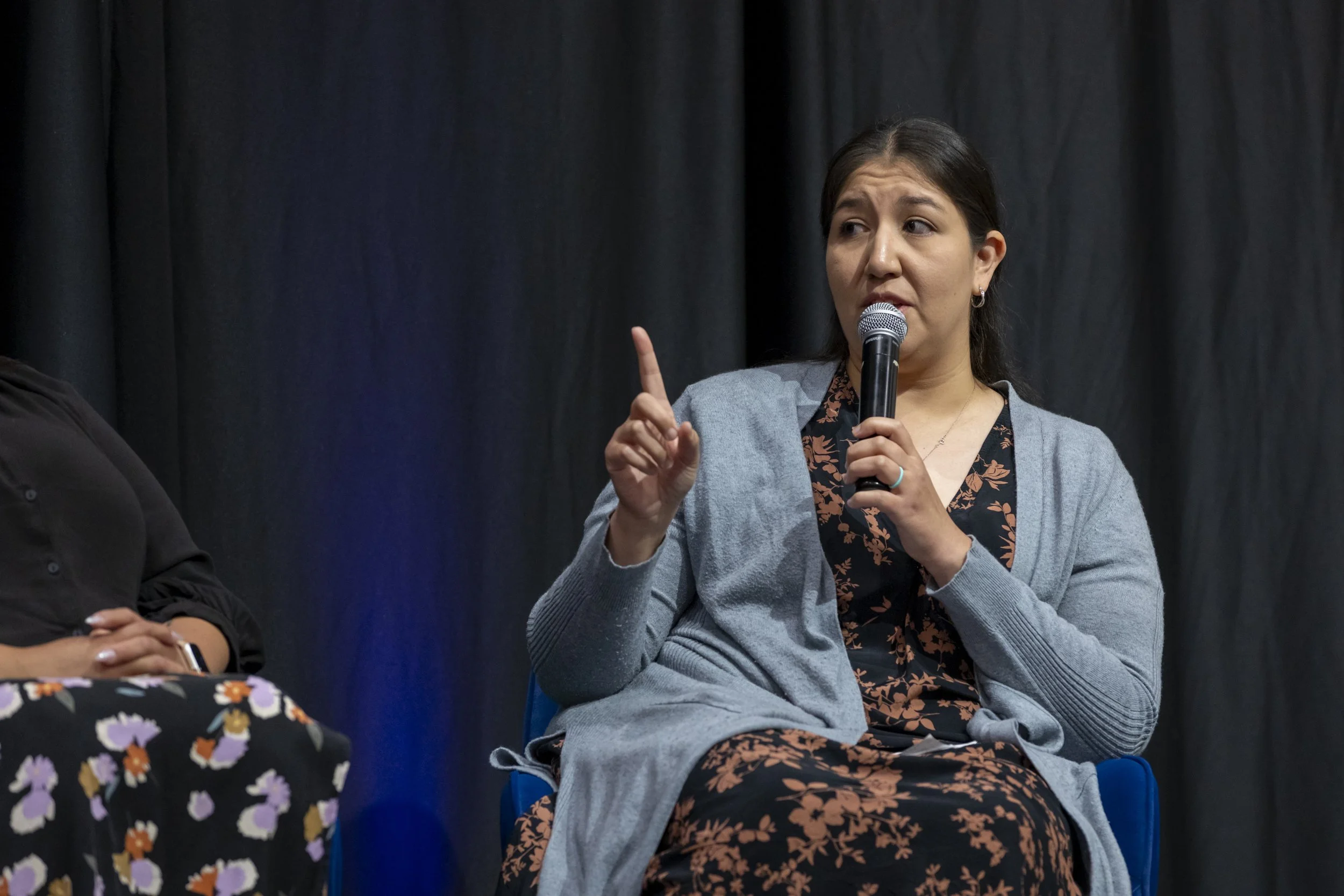 A woman speaking into a mic on stage