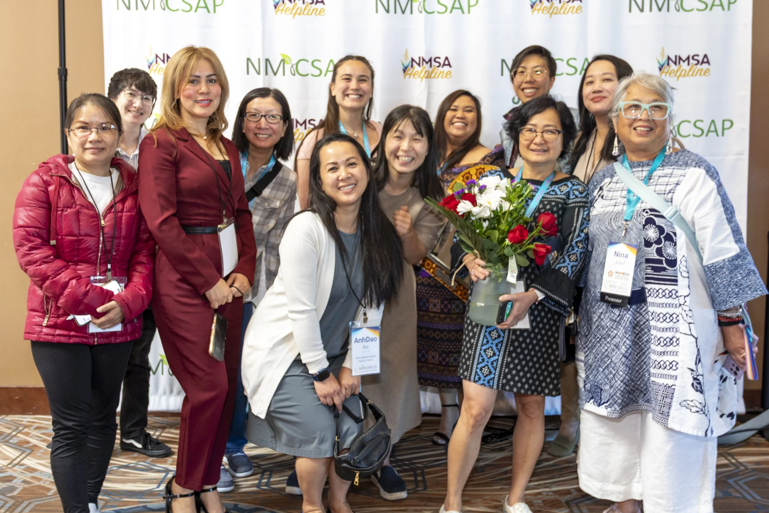 A group of people smiling for a photo and holding flowers