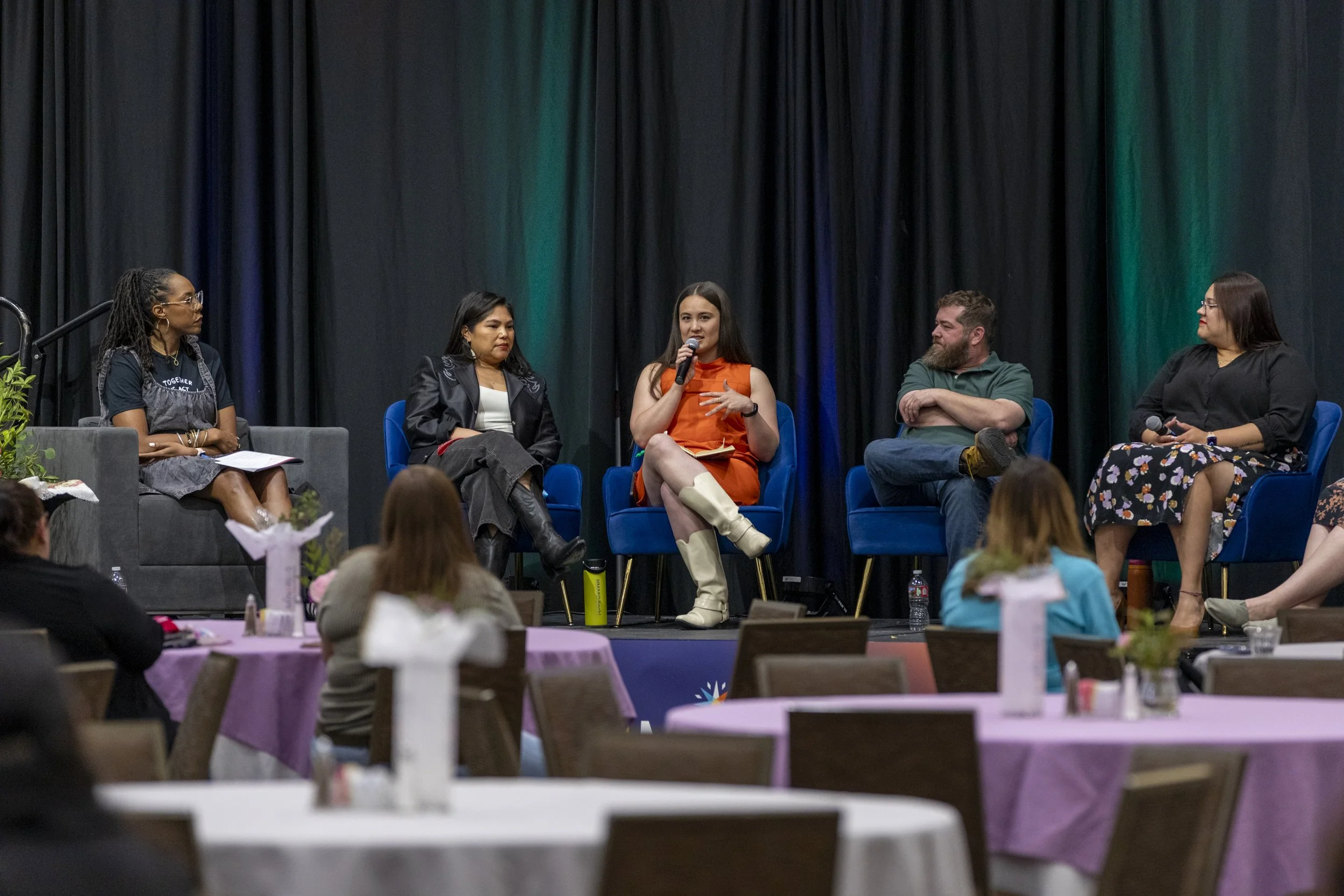 A far back picture woman on a panel speaking