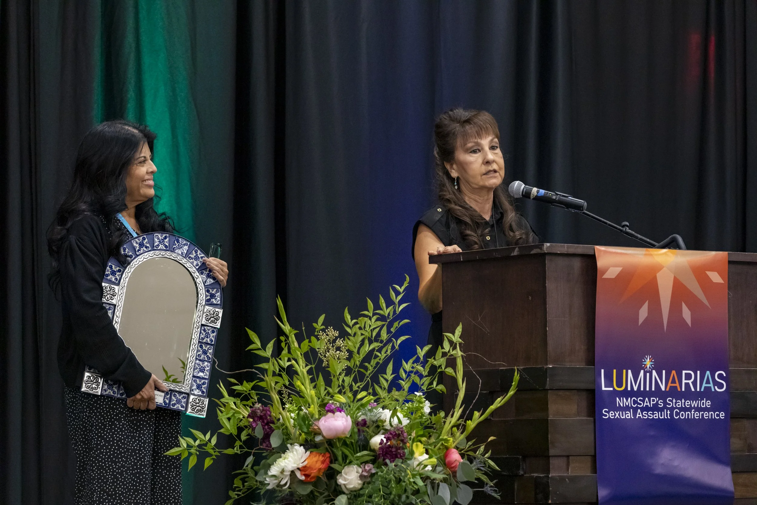 A woman speaking at the podium while another woman holds her award